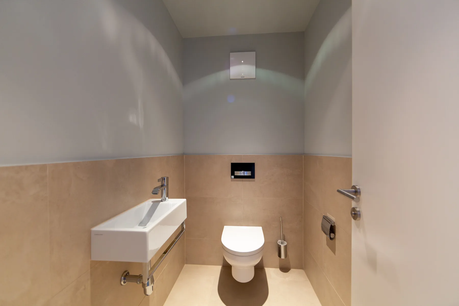 A compact bathroom with a wall-mounted sink and toilet.