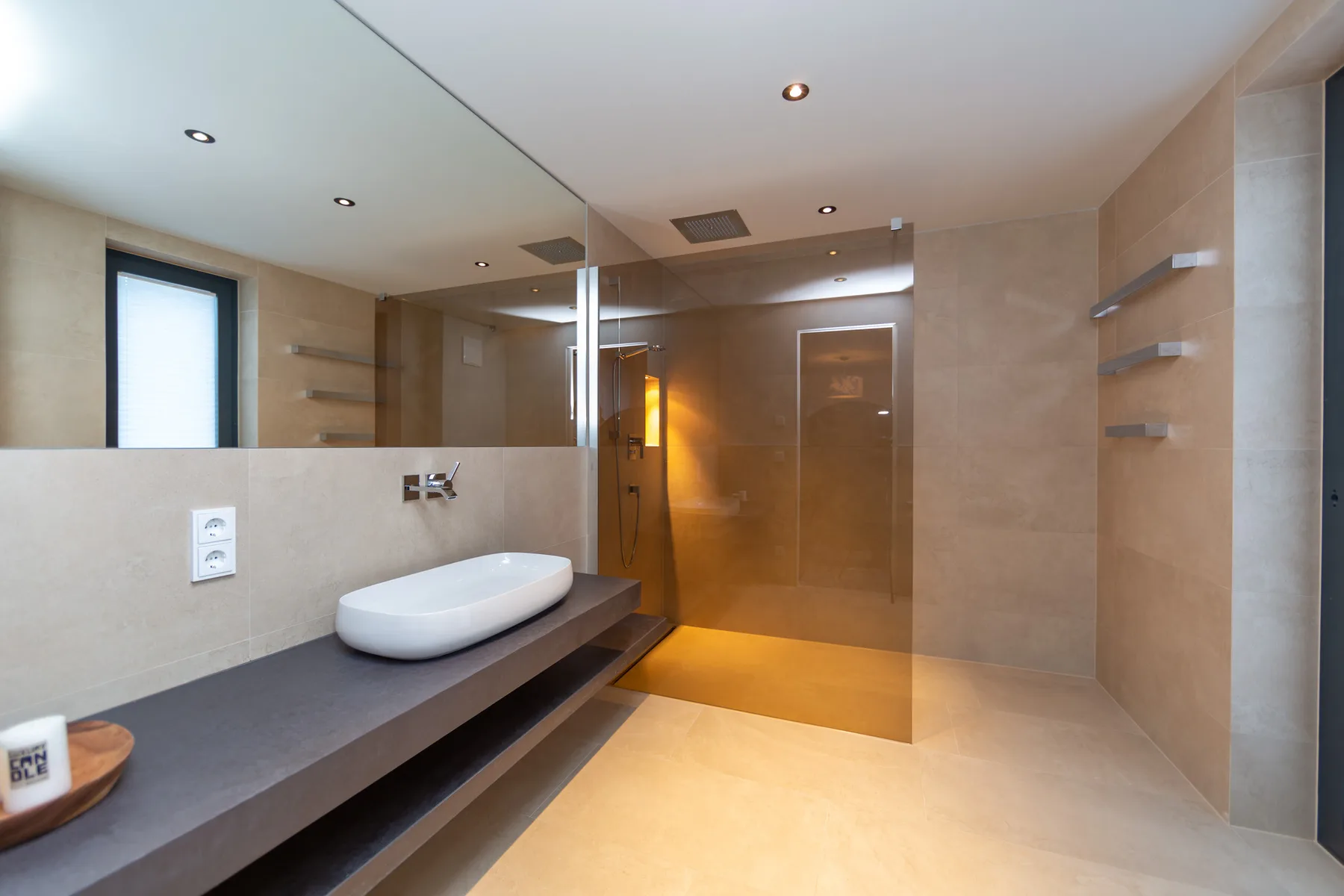 A modern bathroom with a wide vanity, basin, and glass shower.