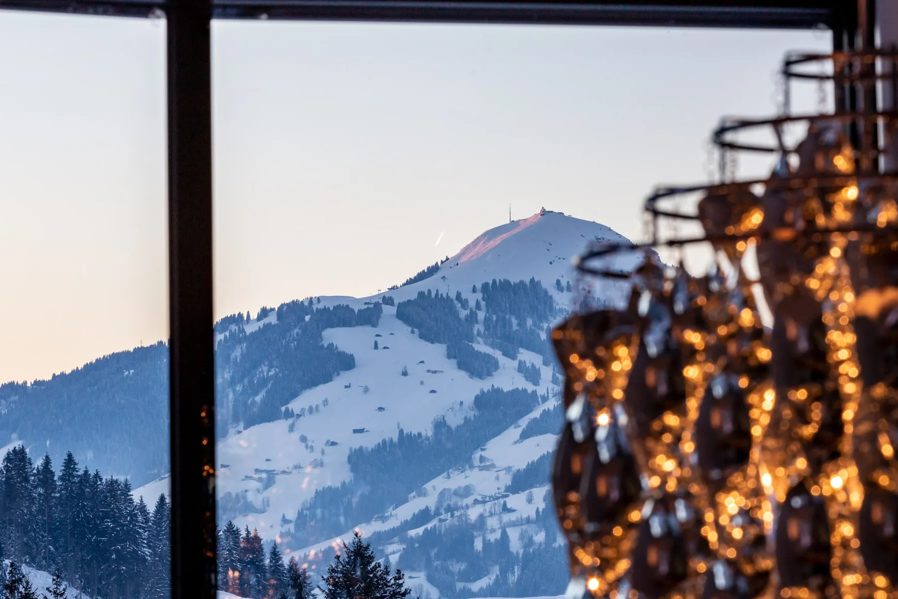 A snowy mountain is visible through a window beside glowing decorative lights.