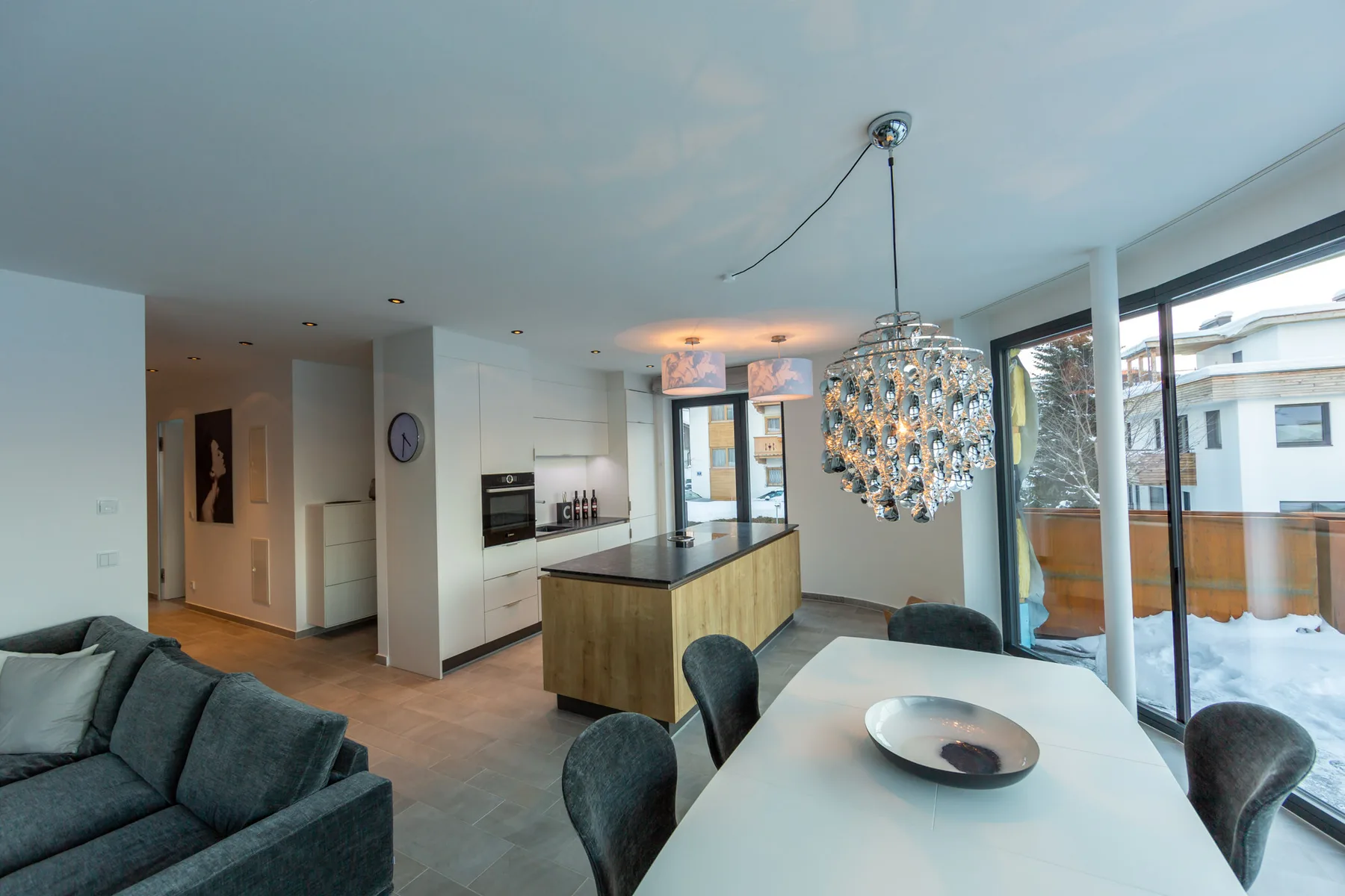 An open-plan kitchen and dining area with a long table and large windows.