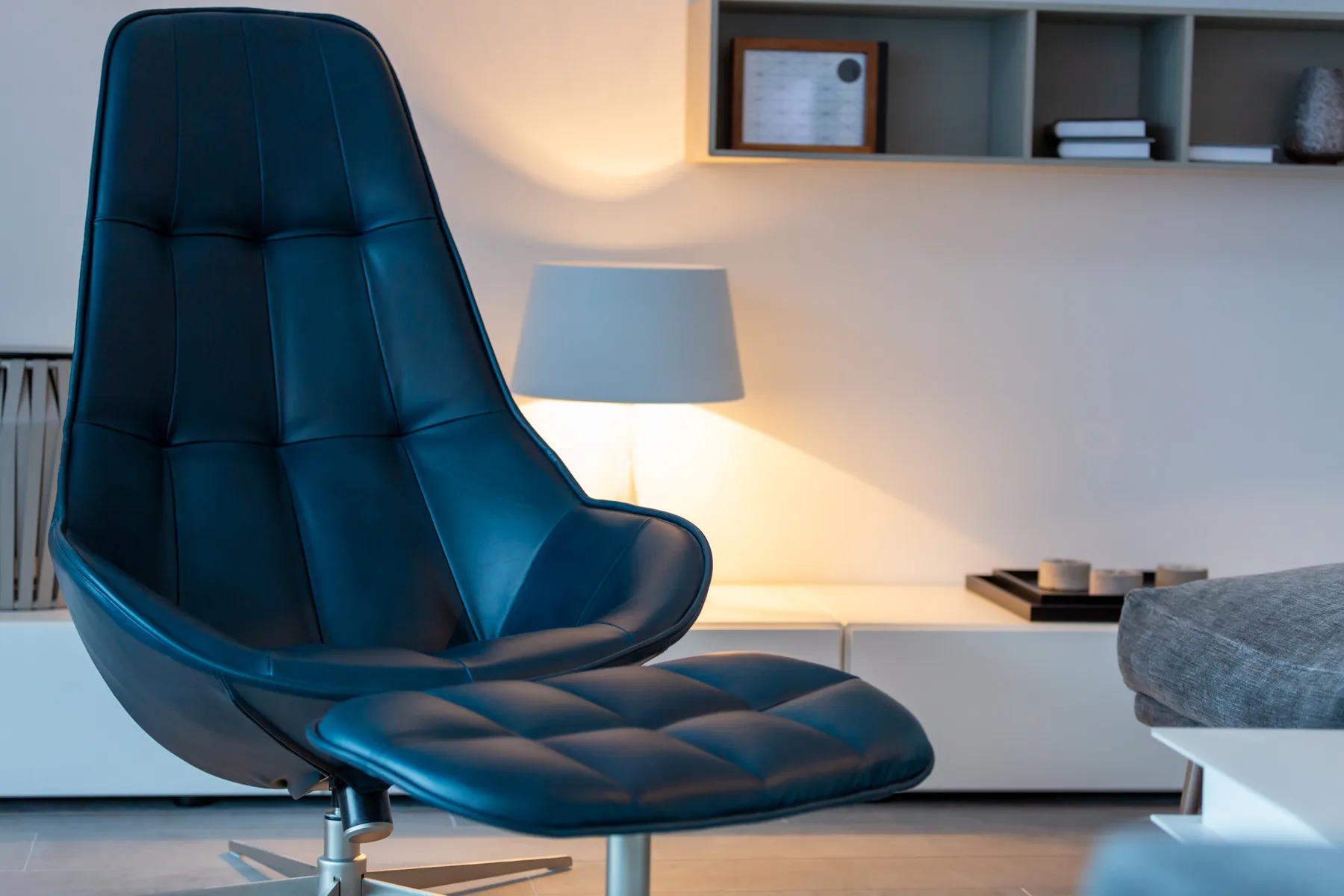 A modern lounge seating area with a tall dark chair beside a lamp.