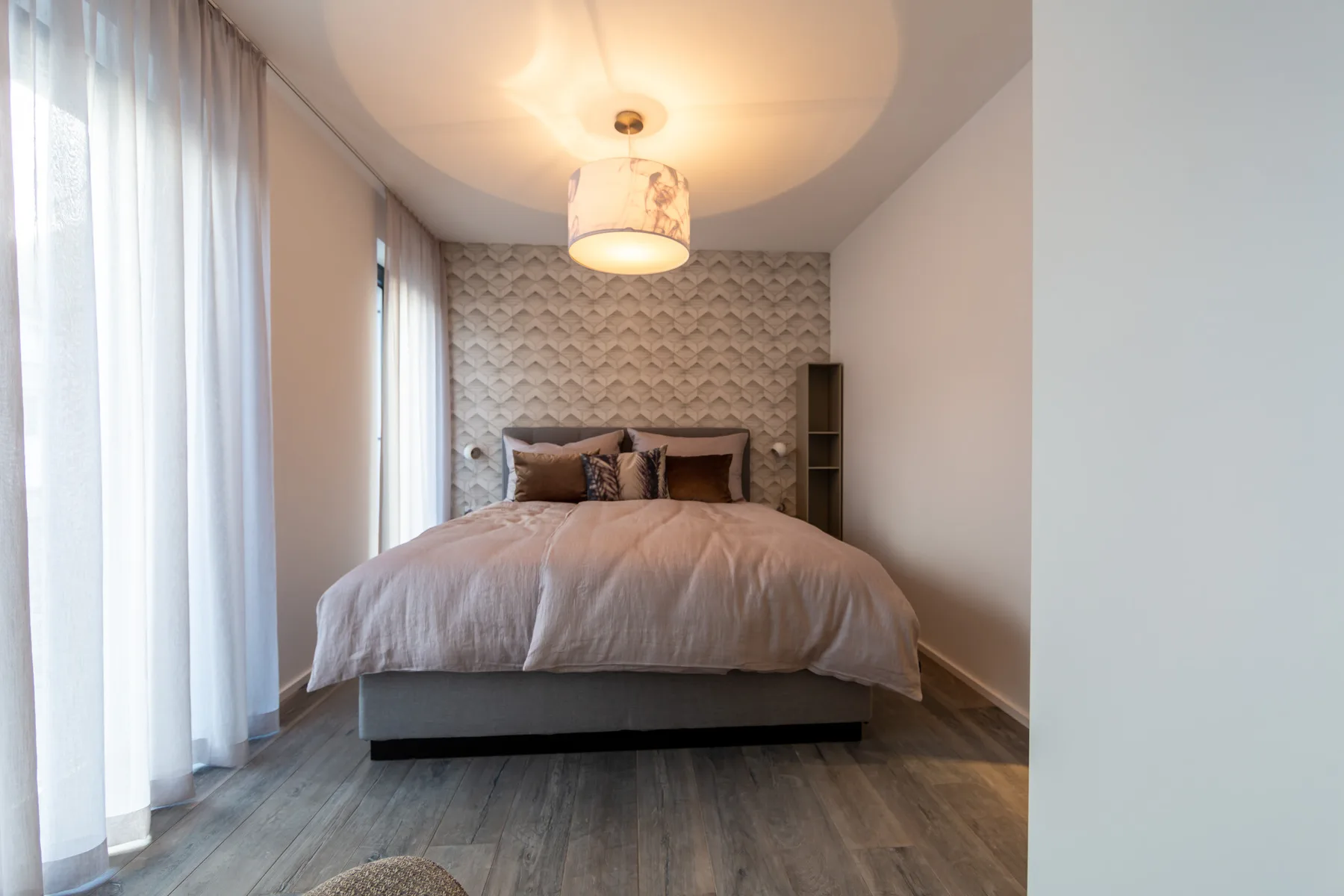 A bedroom with a bed set against a patterned wall.