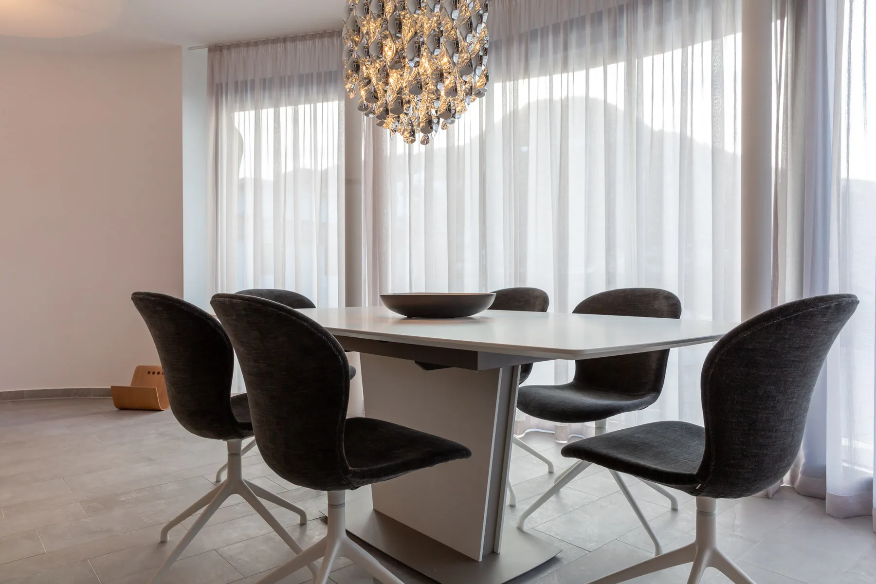 A dining area with a table, dark seating, and a hanging light.