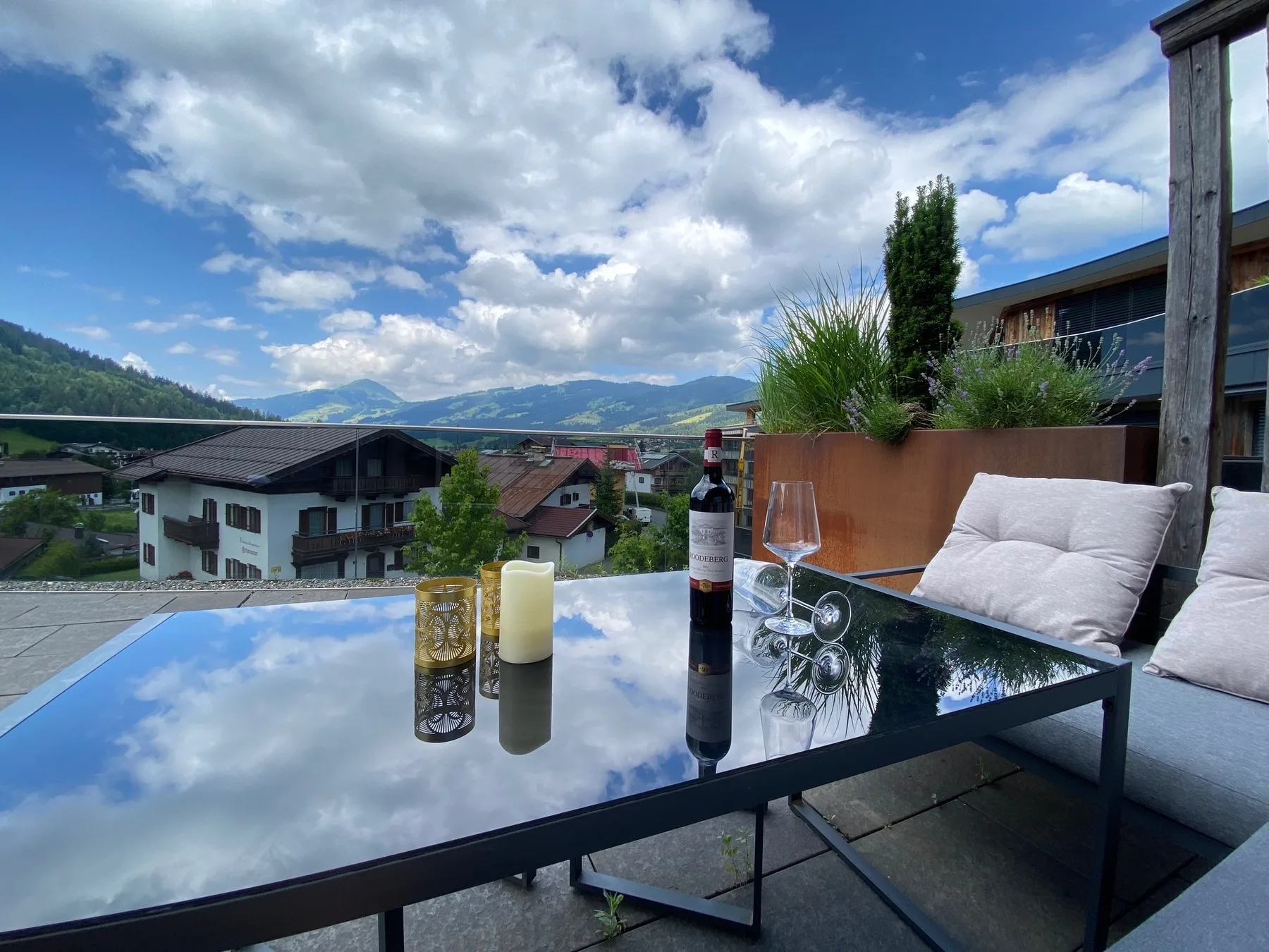 An outdoor terrace seating area overlooks a mountain valley beneath a cloudy sky.