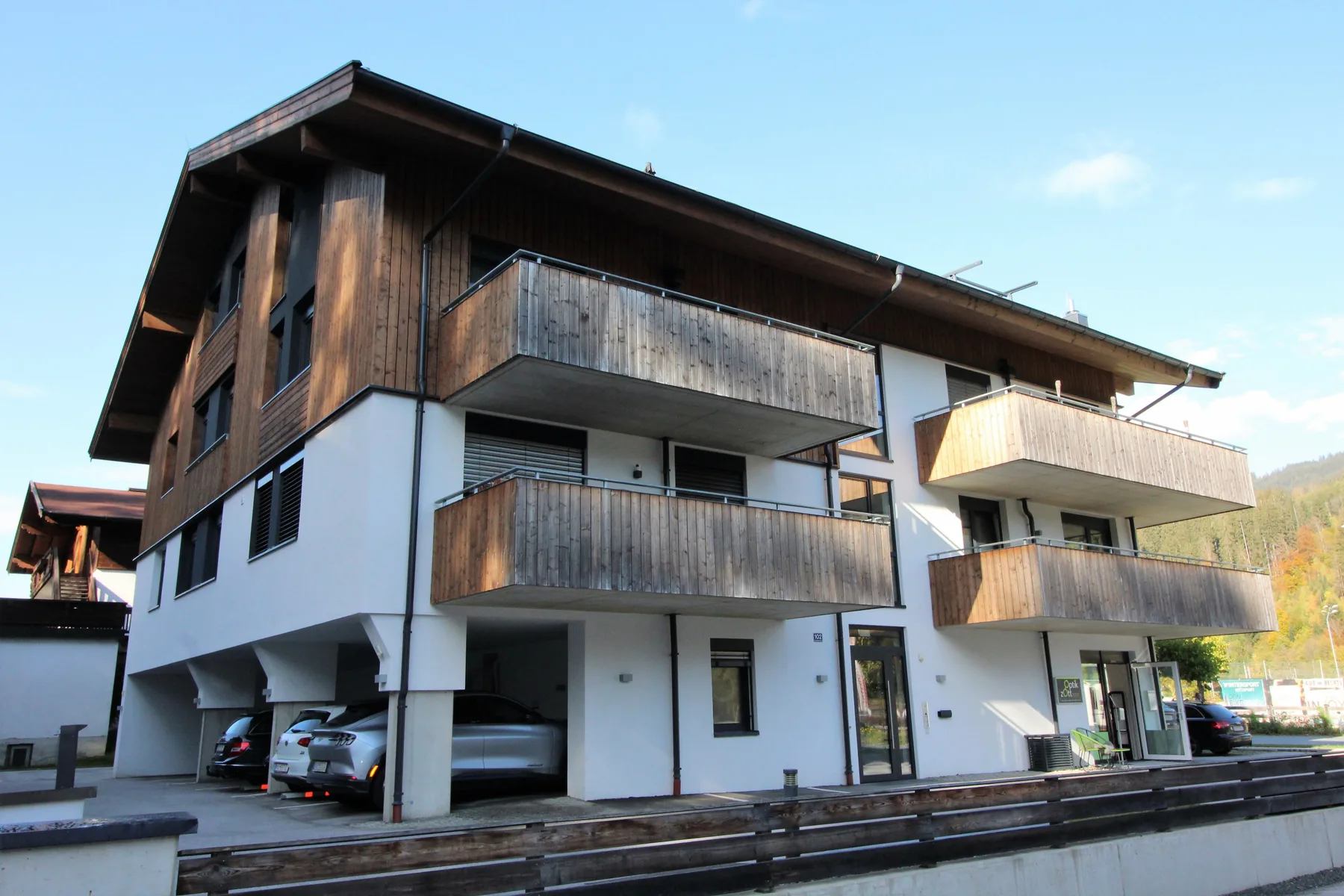 Shared amenity: Apartment building with wooden balconies beneath a clear sky.
