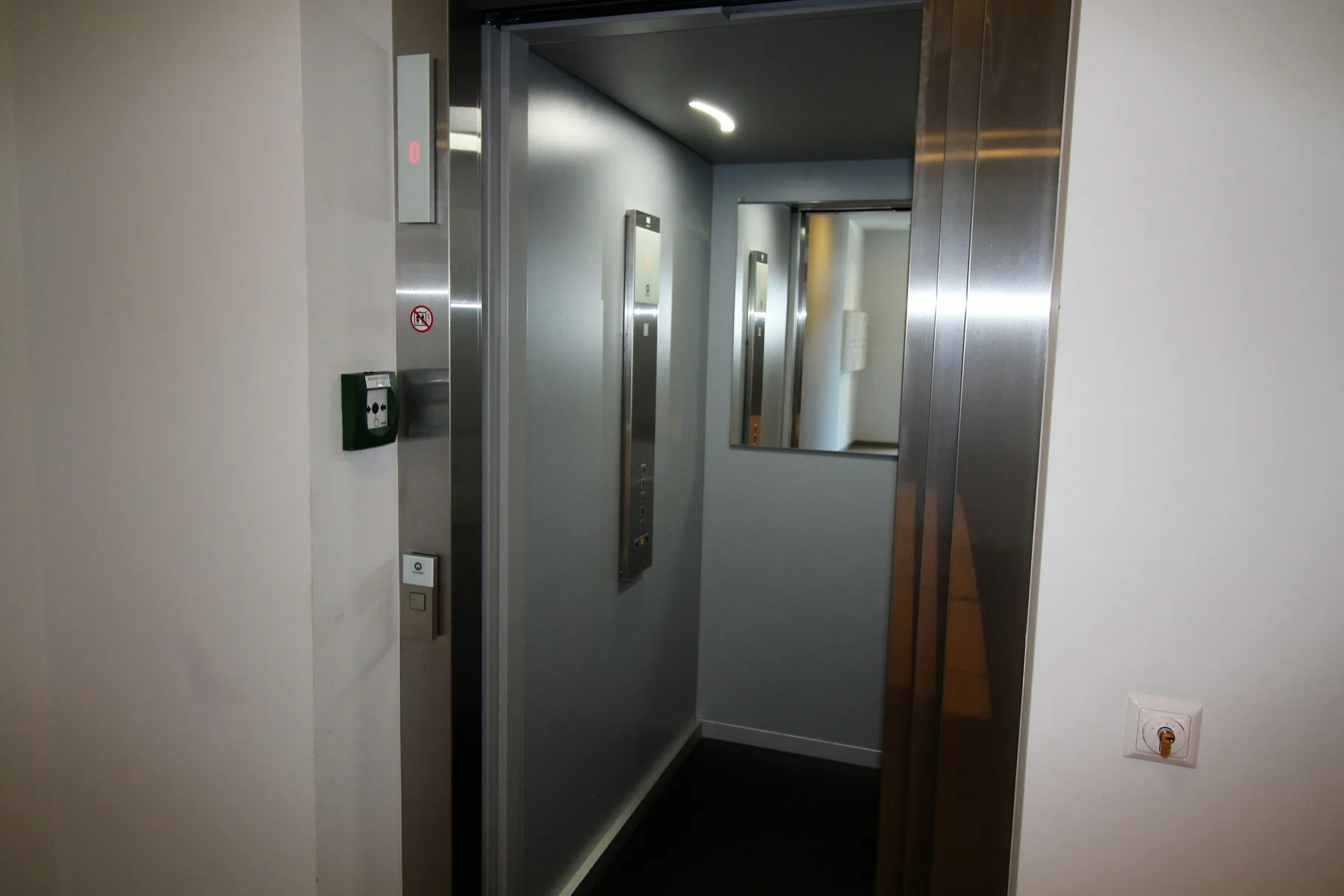 Shared amenity: An elevator doorway opens onto a narrow interior corridor.