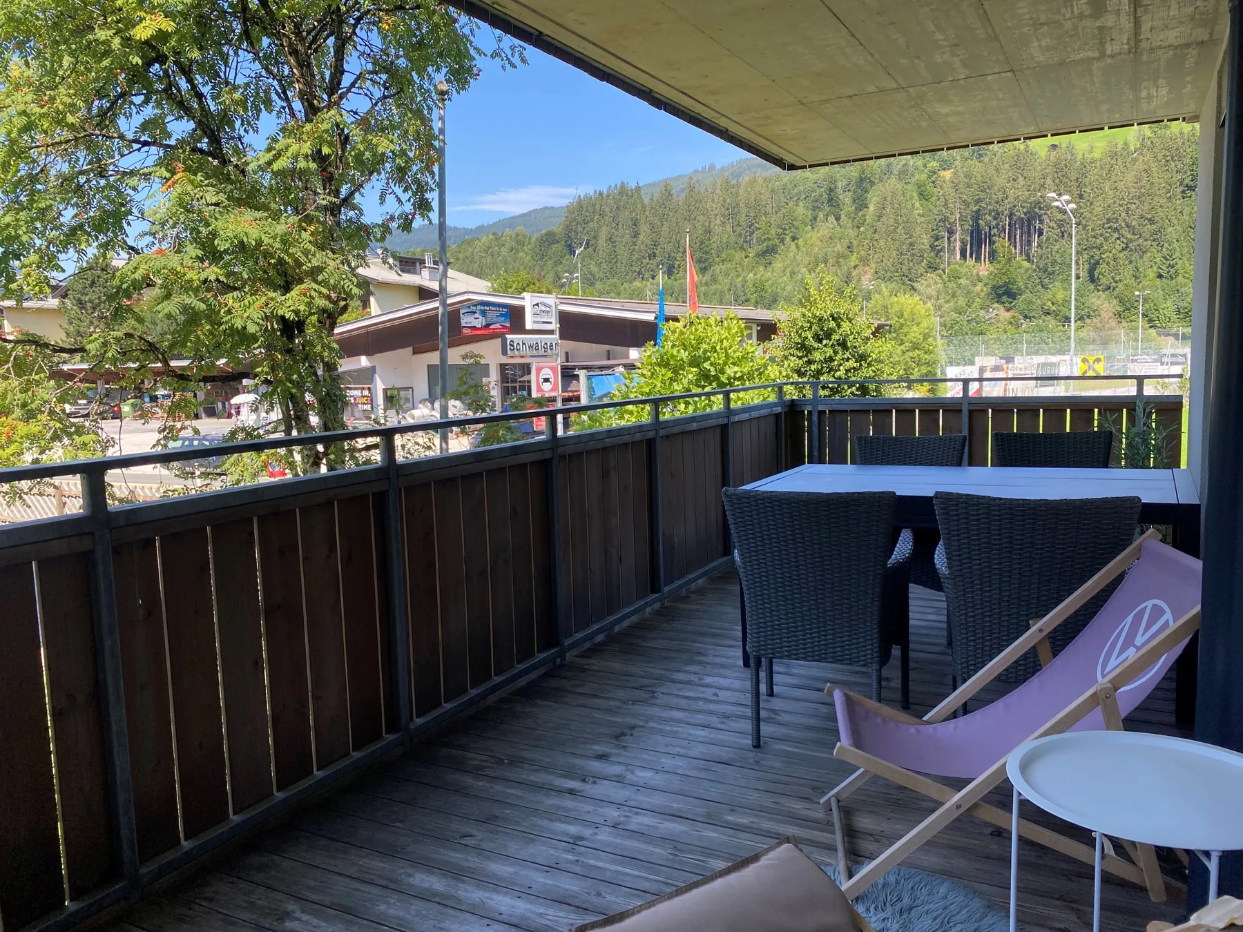 A covered balcony has outdoor seating overlooking a wooded hillside.