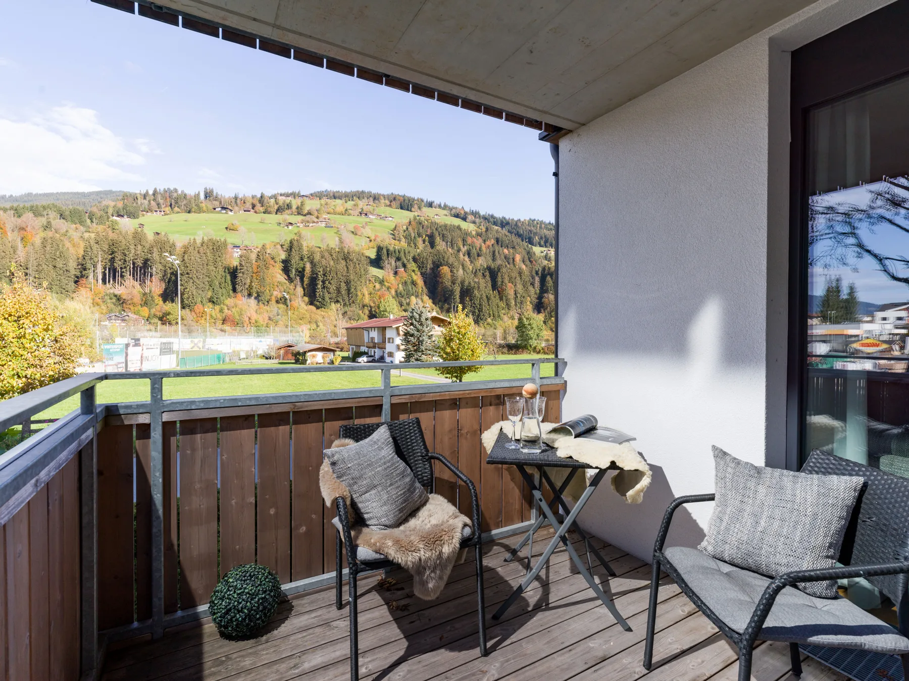 A balcony seating area overlooks wooded hills and a green valley.