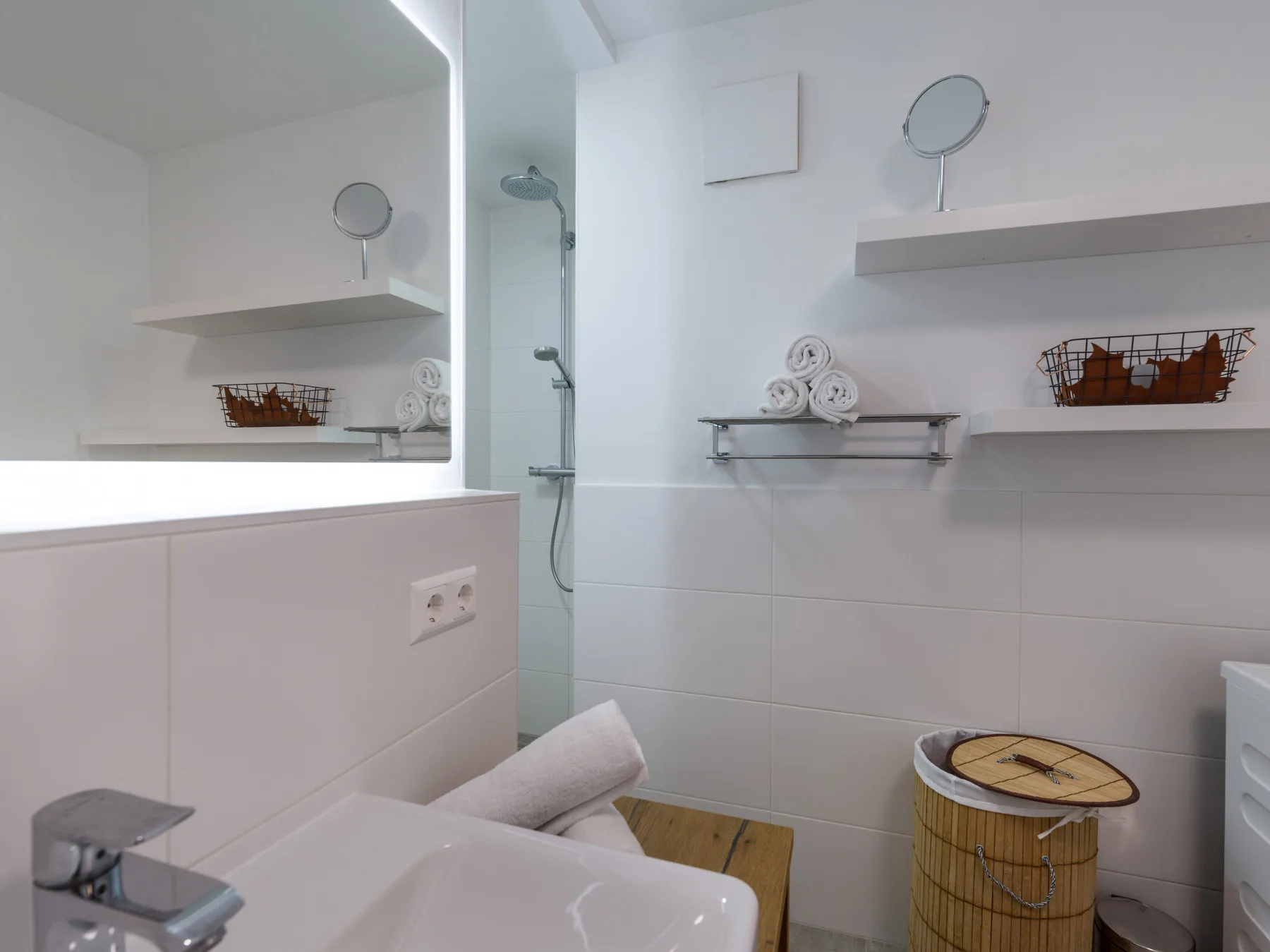 Un baño luminoso con azulejos, ducha de pared y un pequeño taburete de madera.