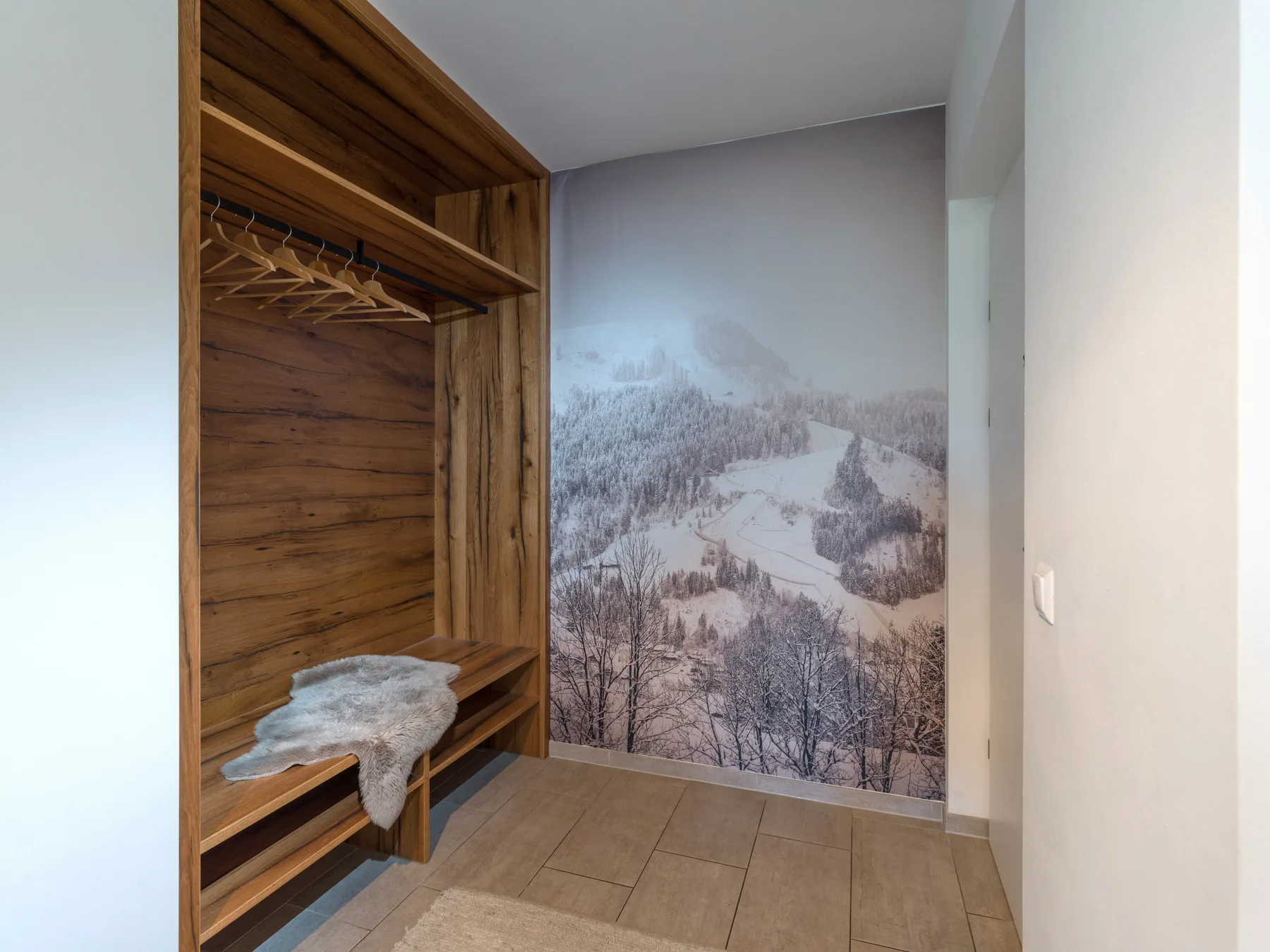 A wood-paneled entry area has open hanging space and a snowy landscape mural.