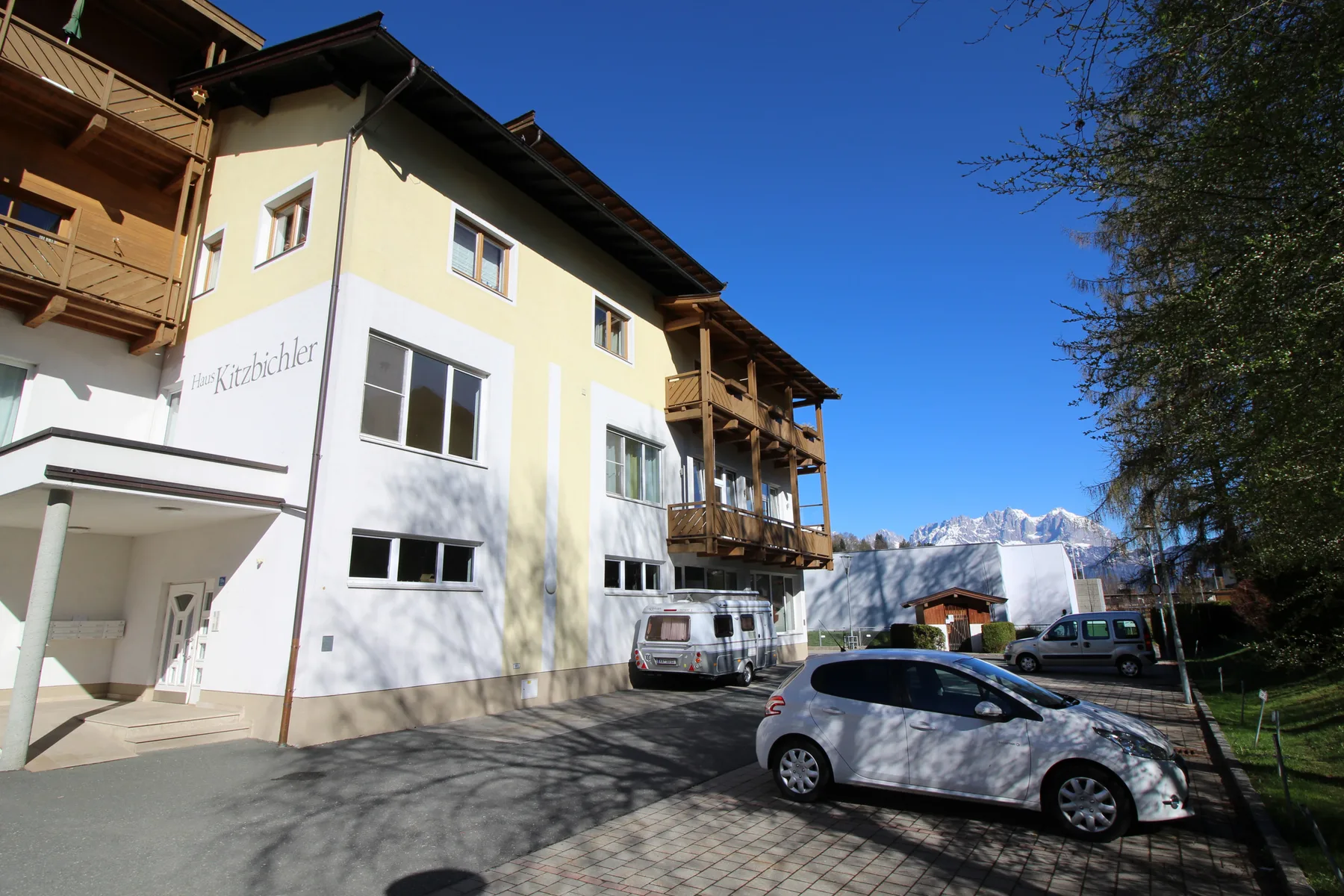 Shared amenity: An apartment building stands beside a paved parking area with parked cars.