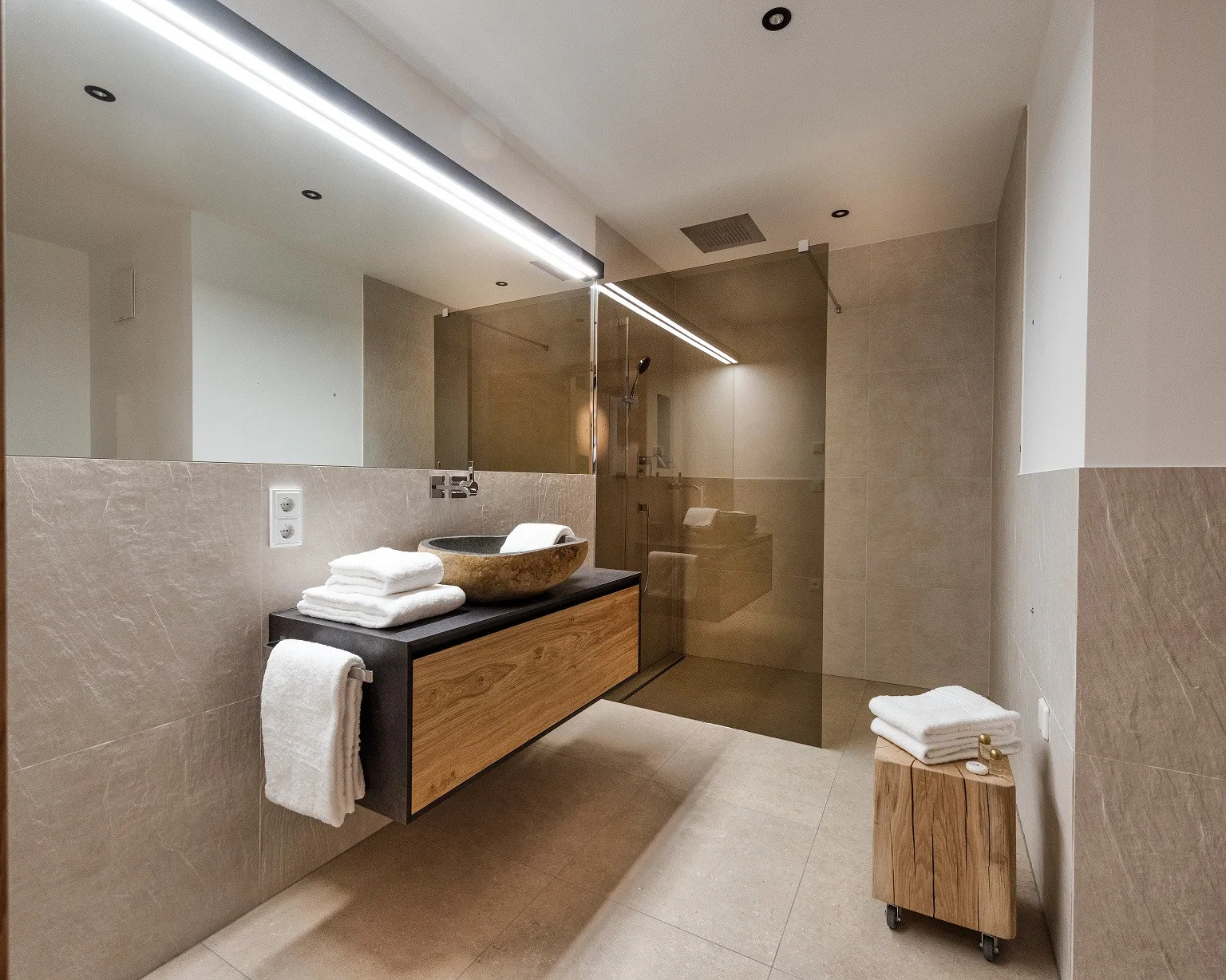 Un baño moderno con un lavabo suspendido, espejo y ducha de vidrio.