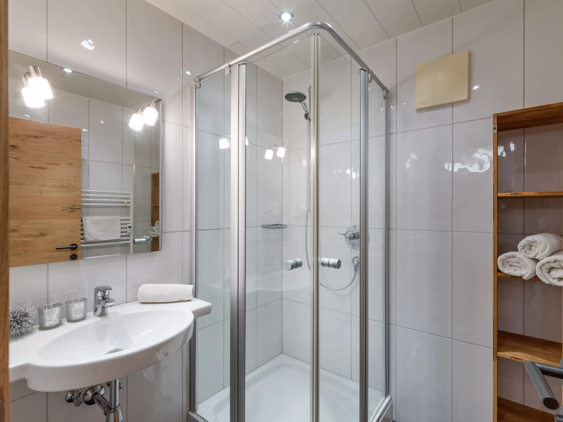 A tiled bathroom with a glass shower and a sink beside a mirrored cabinet.