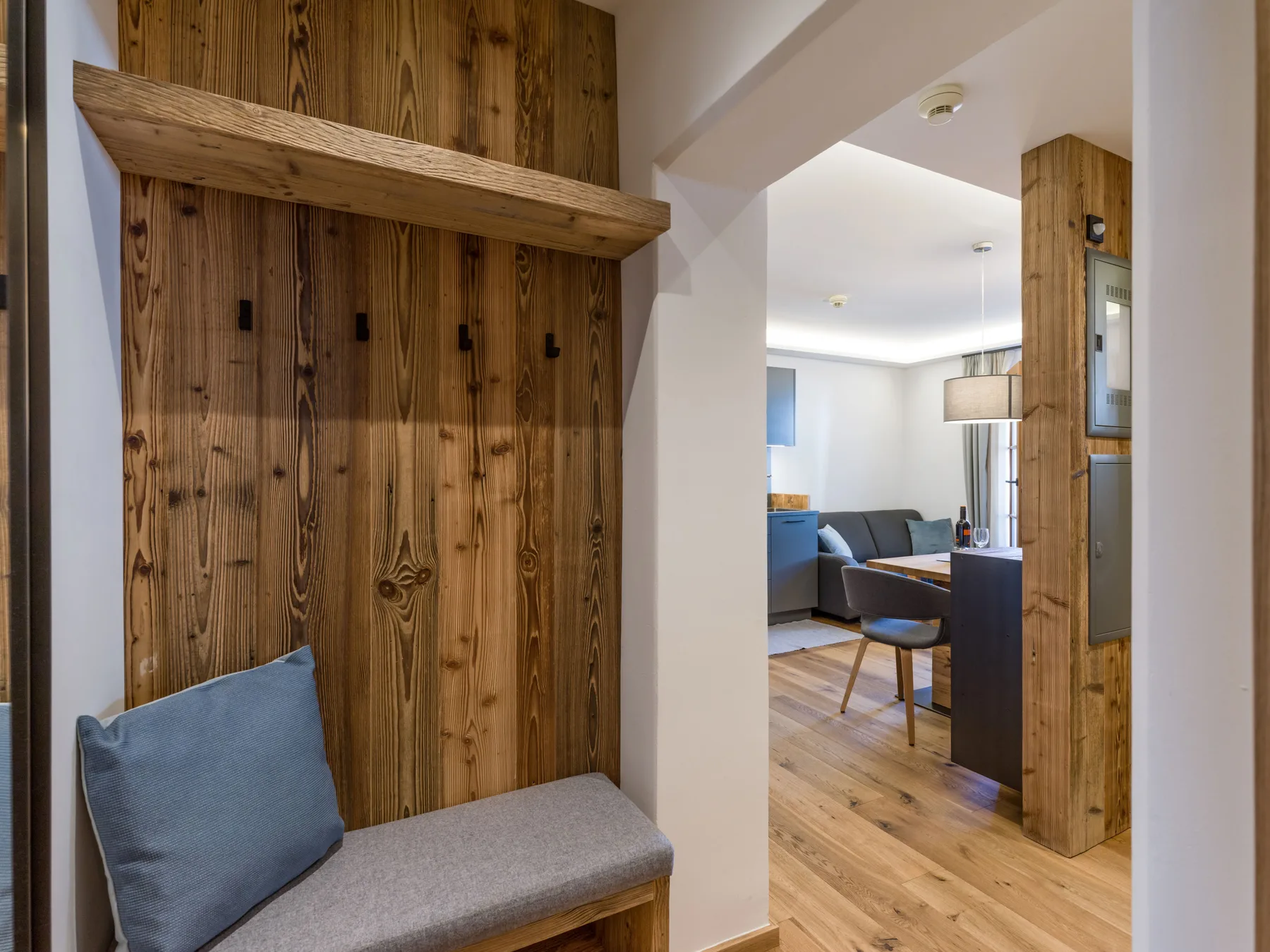 A wood-paneled entry area opens into a living room with seating and a table.
