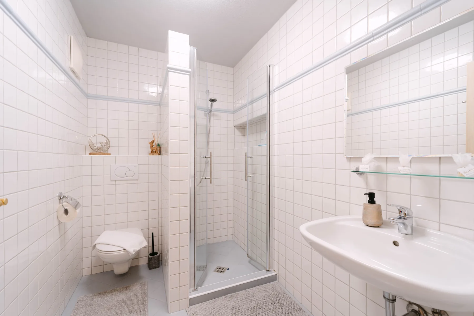 Un baño alicatado con una ducha de vidrio y un lavabo.