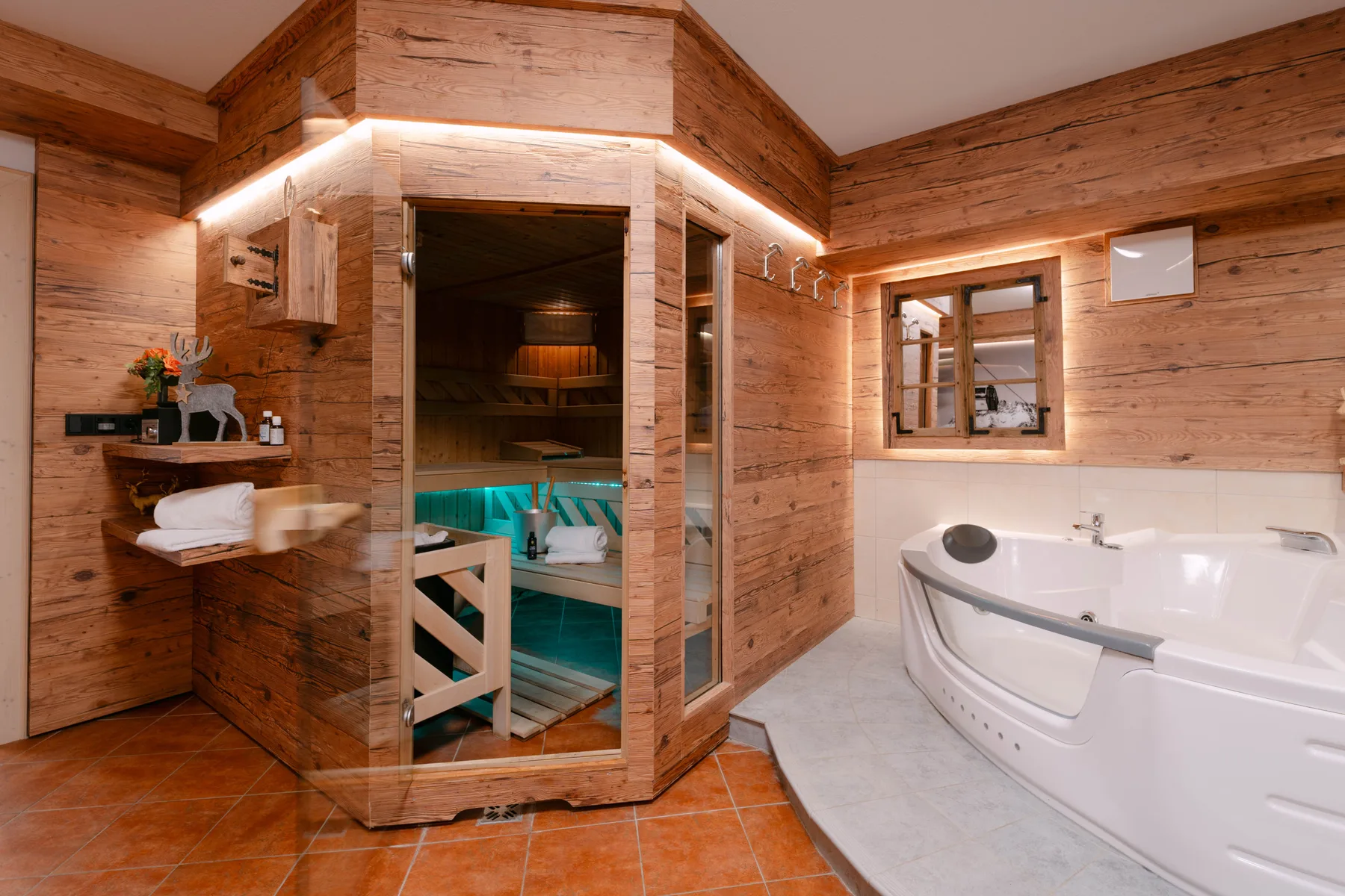 Un baño revestido de madera con una bañera grande y una sauna con frente de vidrio.