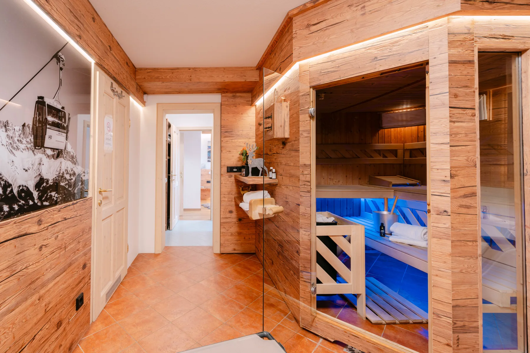 Un pasillo de madera da a una sauna con asientos iluminados en azul.