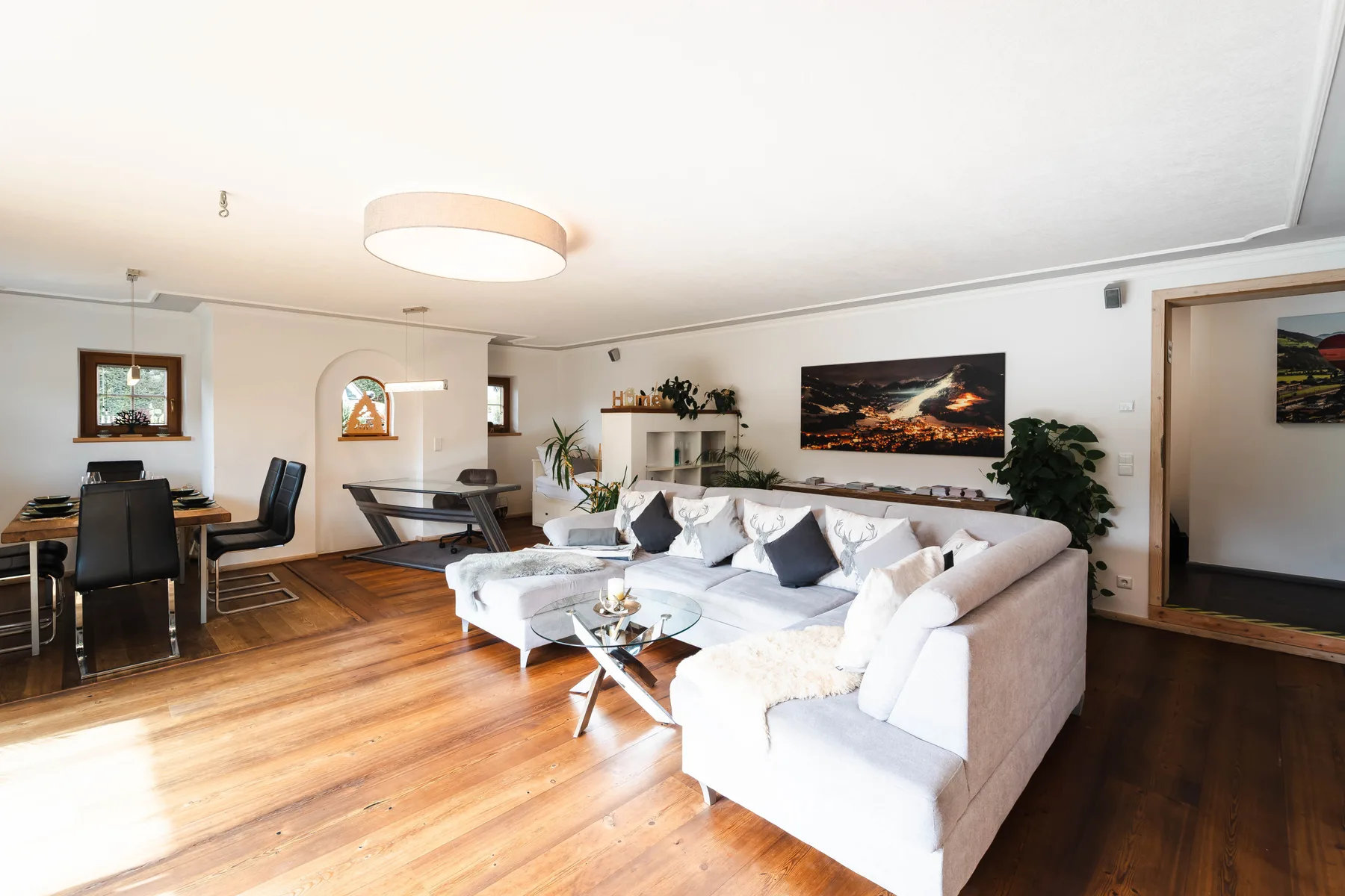 Una sala luminosa con una zona de asientos y suelo de madera.