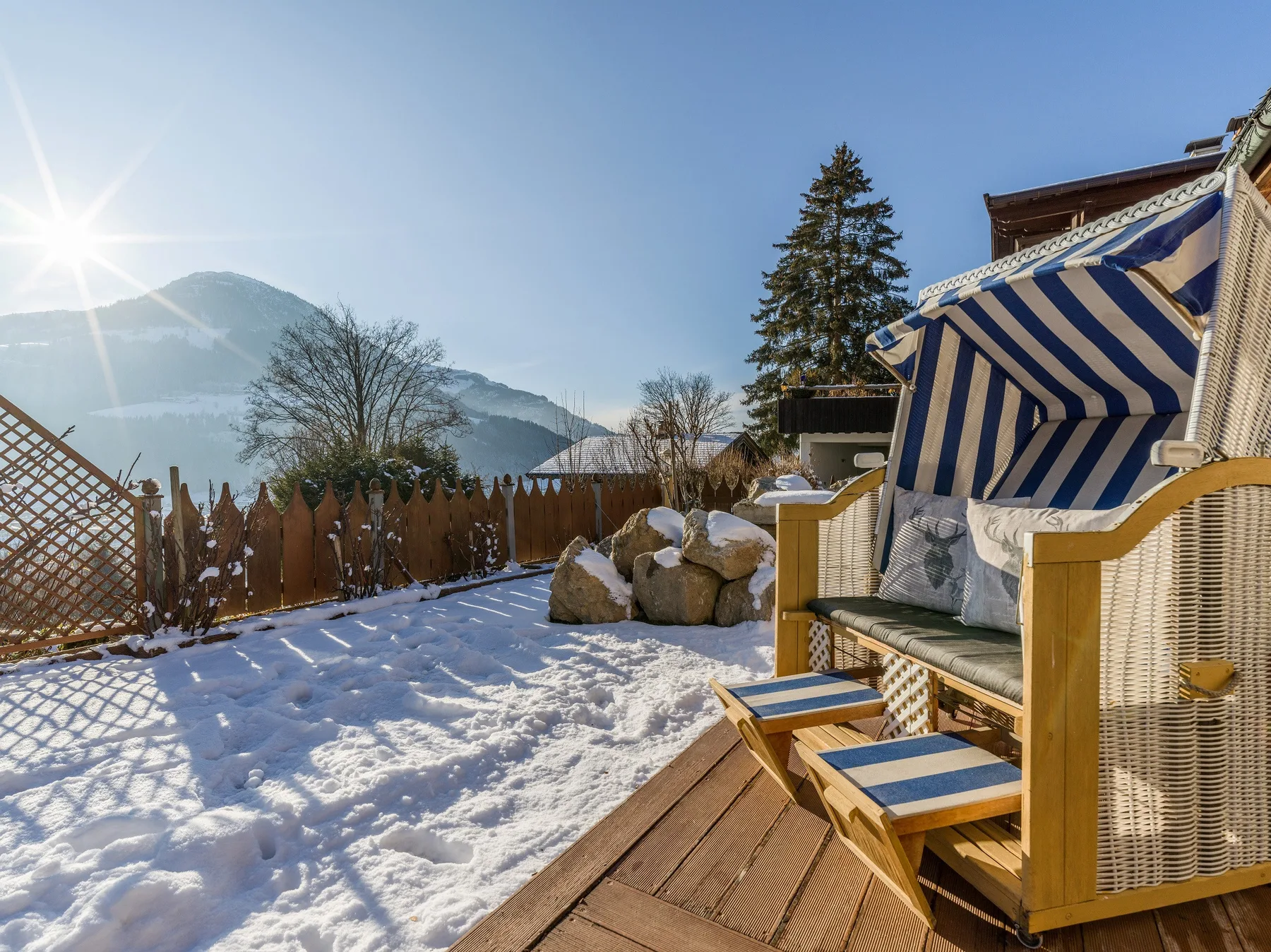Una terraza exterior cubierta de nieve con asientos a rayas y vistas a las montañas.
