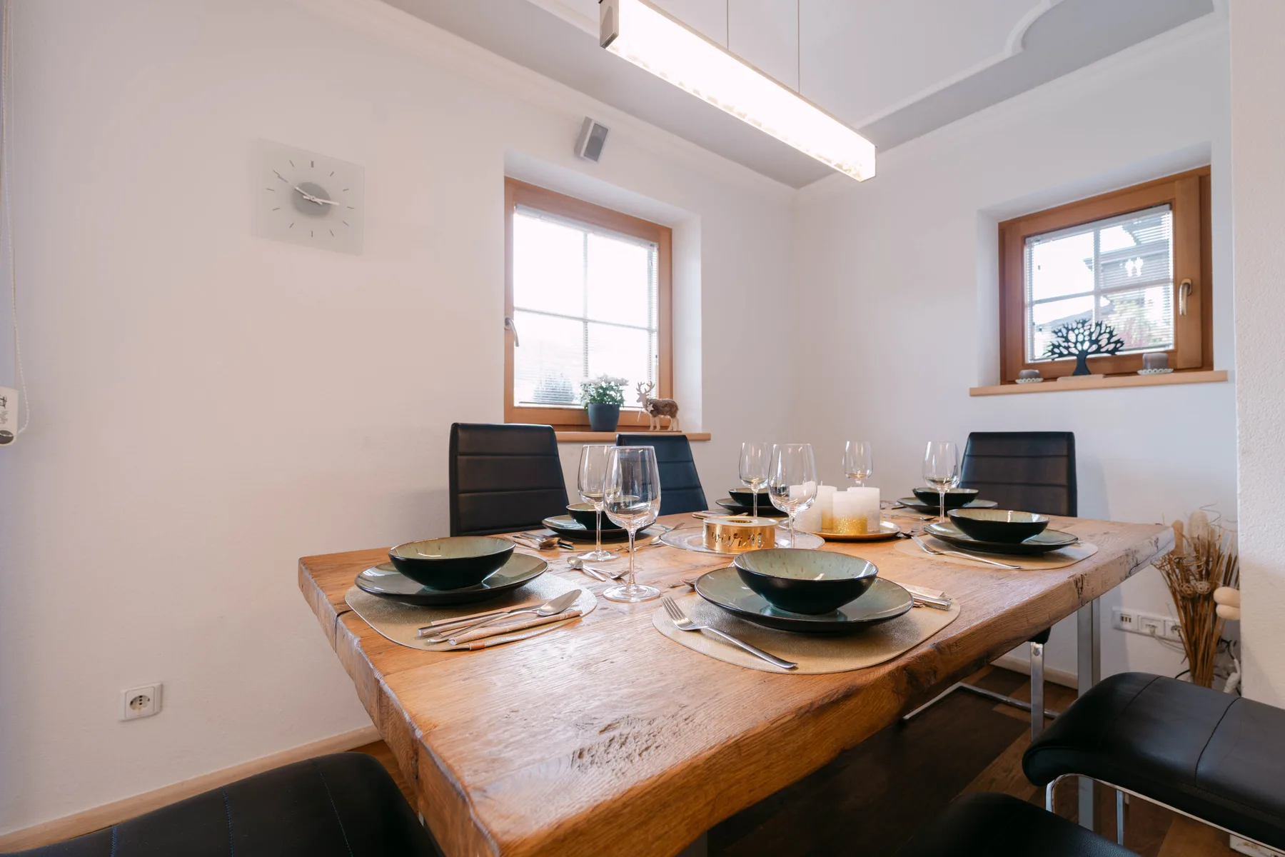 Un comedor con una mesa de madera puesta con platos y cristalería.