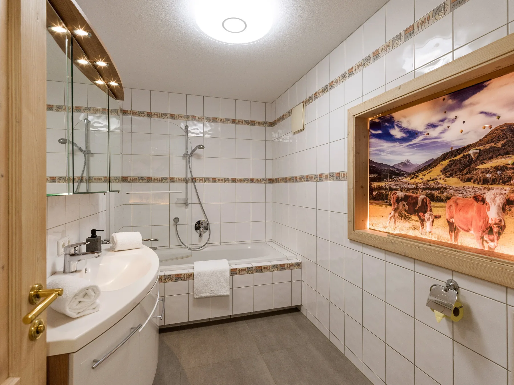 Un baño con azulejos, lavabo, ducha y un cuadro enmarcado en la pared.