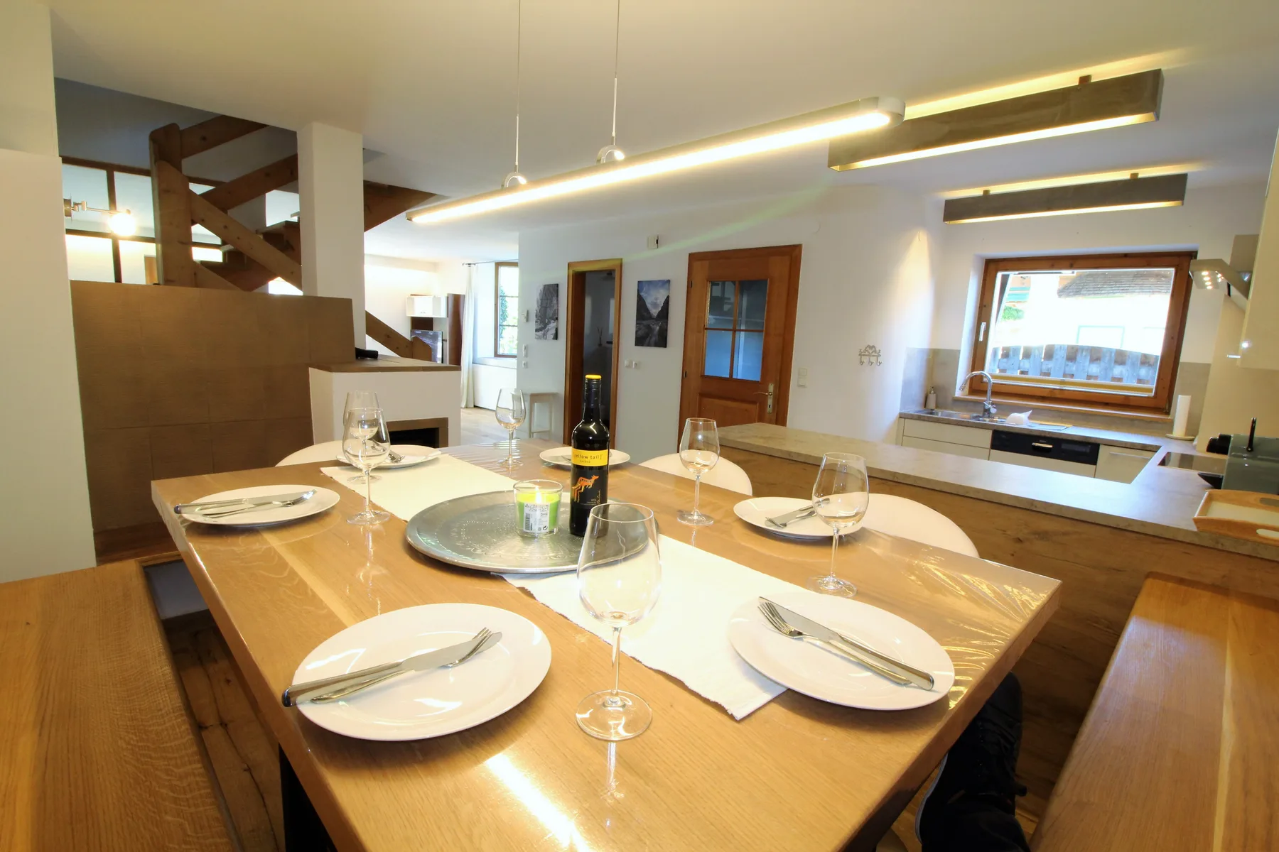 Comedor con una gran mesa de madera preparada con platos y vasos.