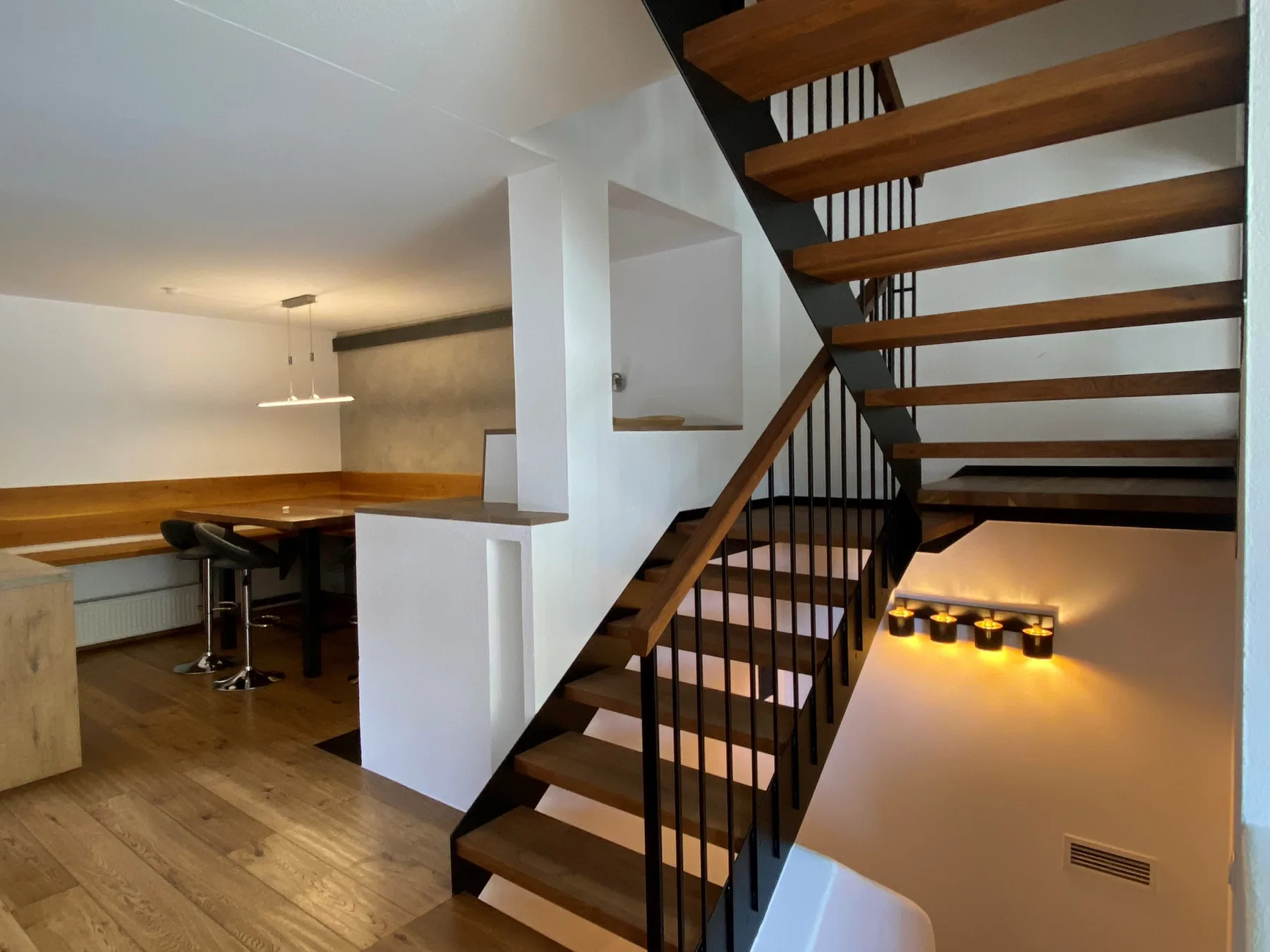 Un interior moderno con una escalera de madera junto a un comedor.
