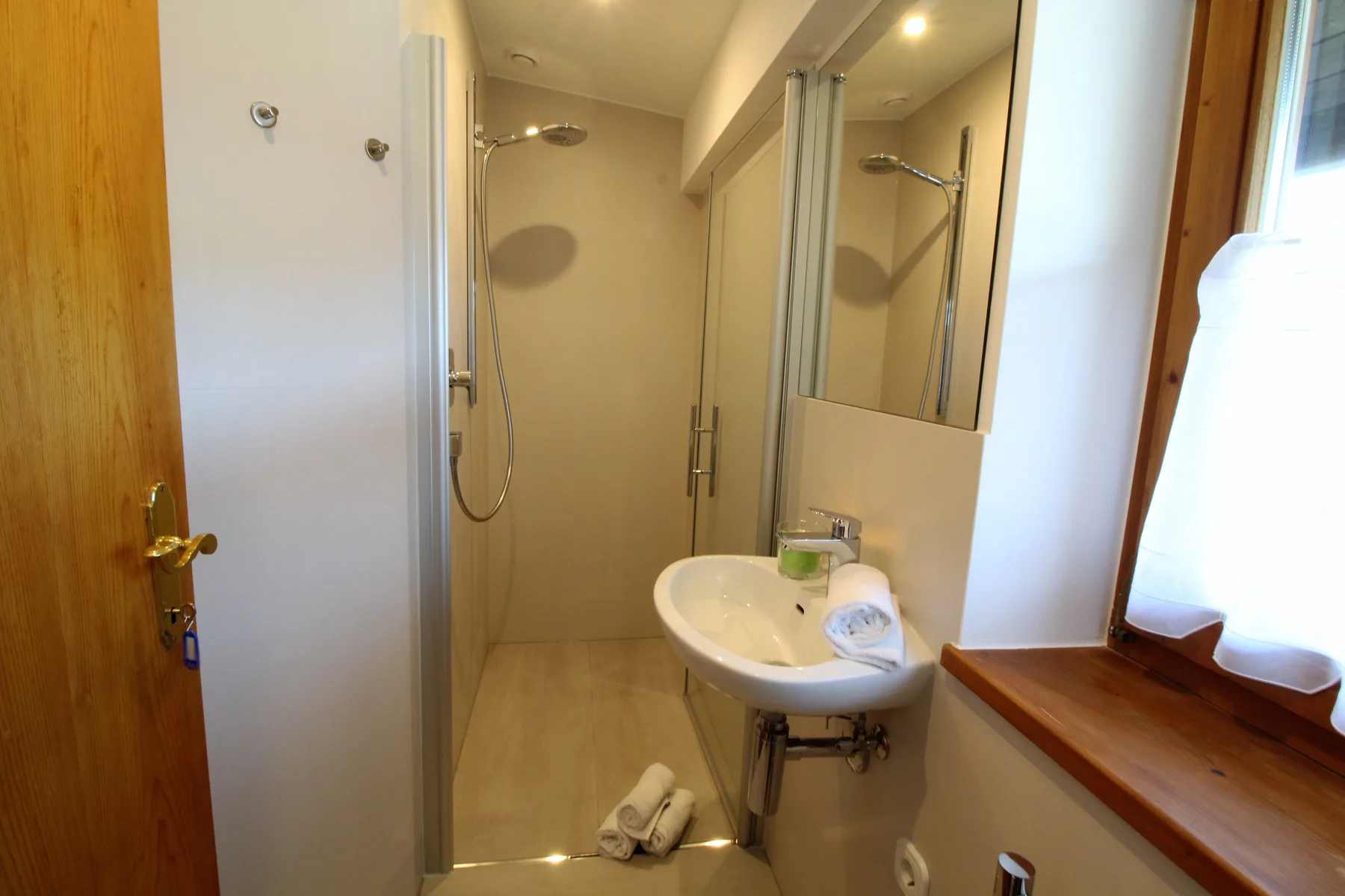 Un baño con ducha, lavabo y ventana.