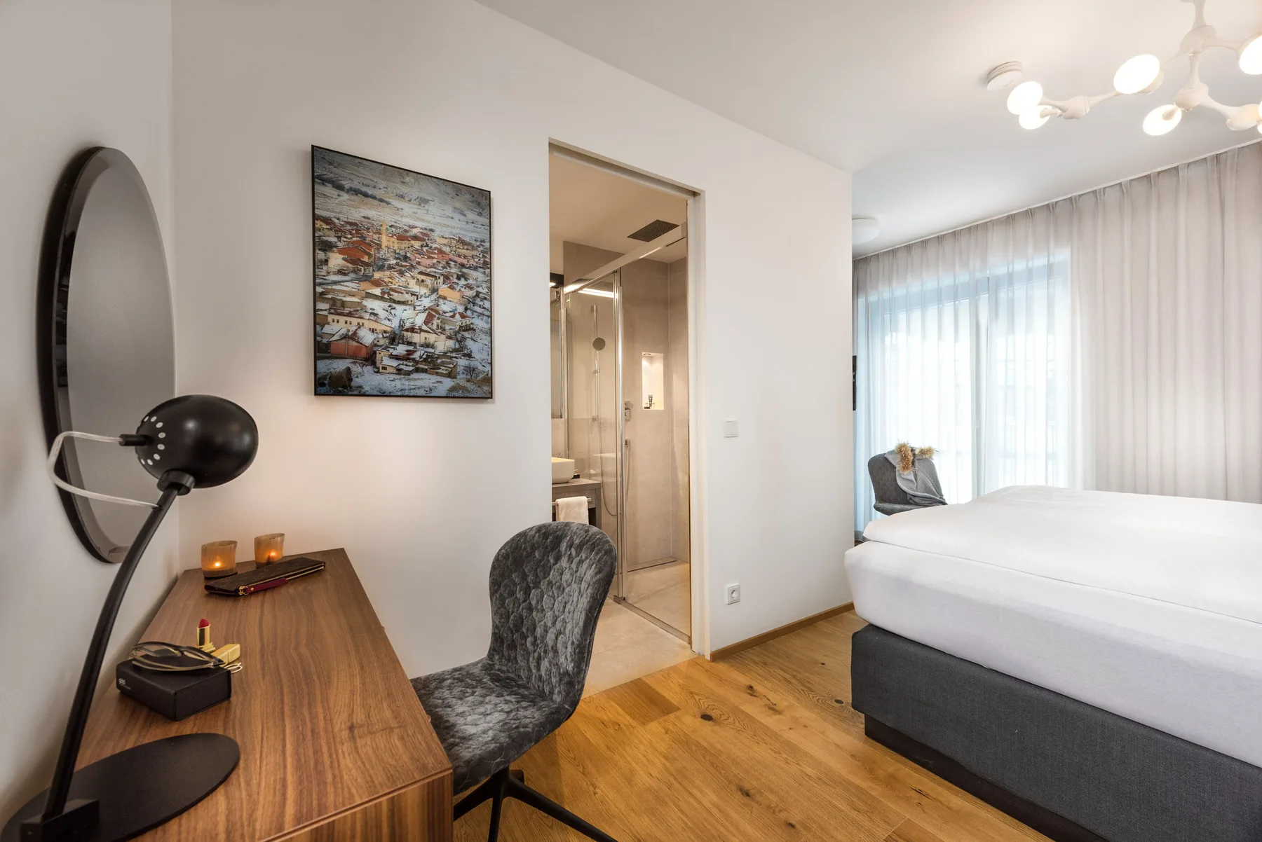 Un dormitorio con una cama, un escritorio y una silla junto a una ventana con cortinas.
