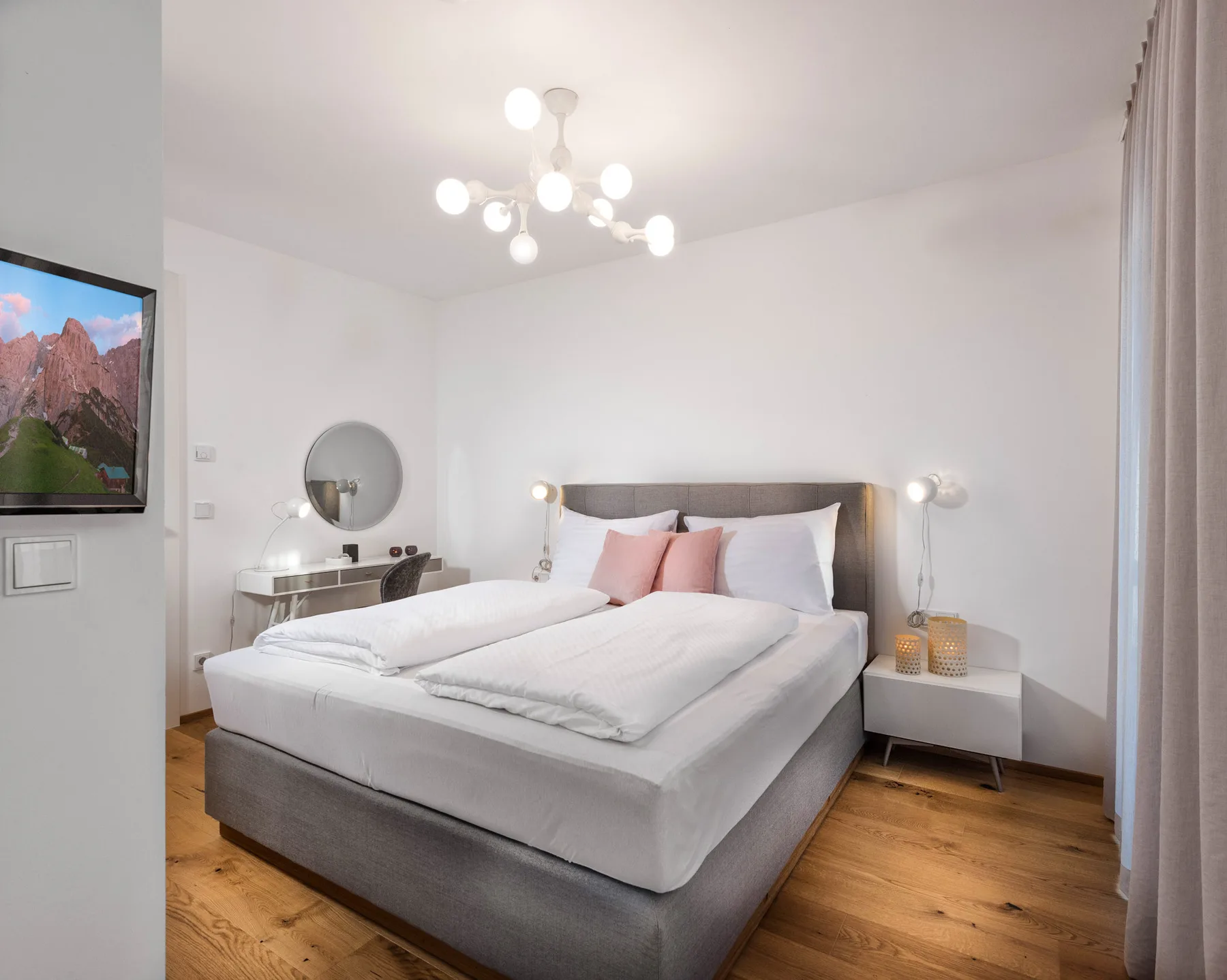 Un dormitorio con una cama grande, mesitas de noche y un televisor montado en la pared.