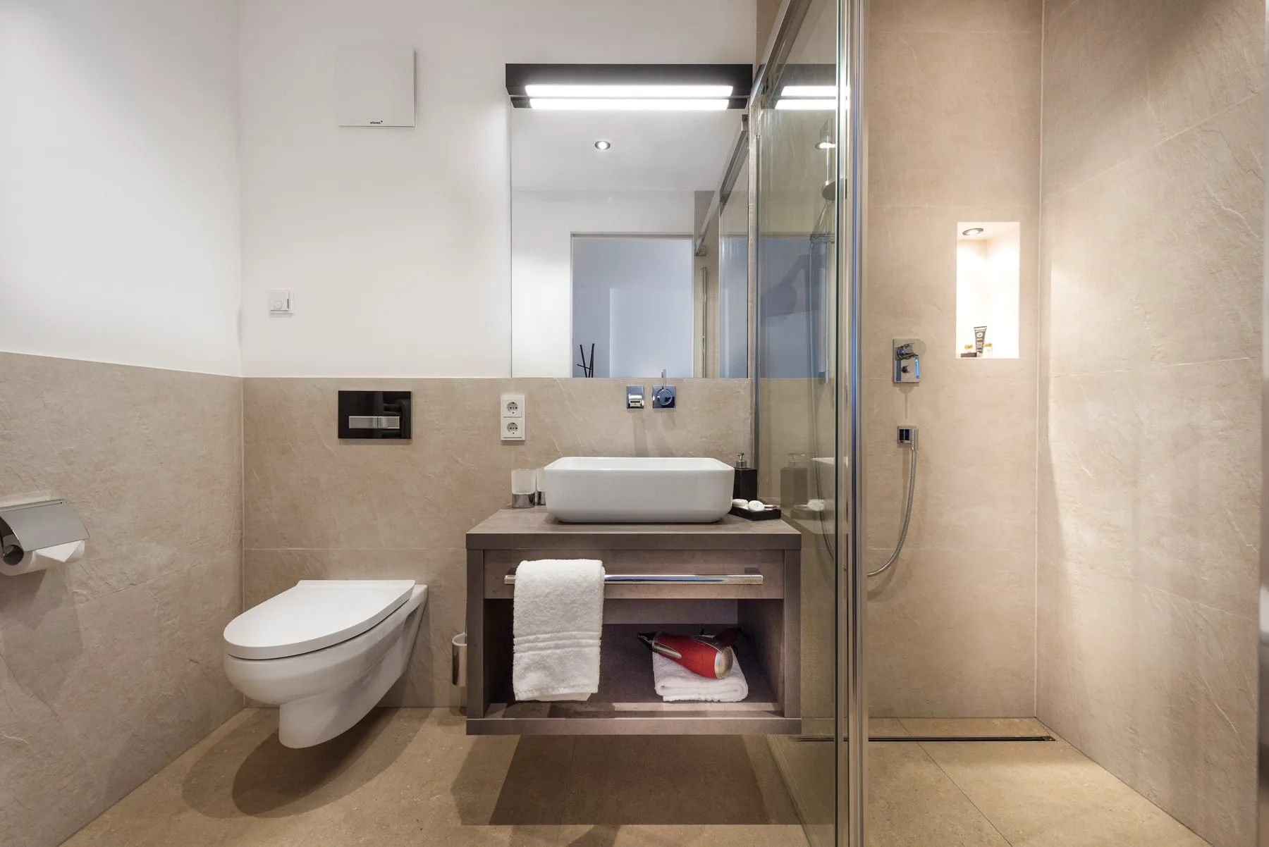 Un baño moderno con lavabo, inodoro y ducha con mampara de vidrio.