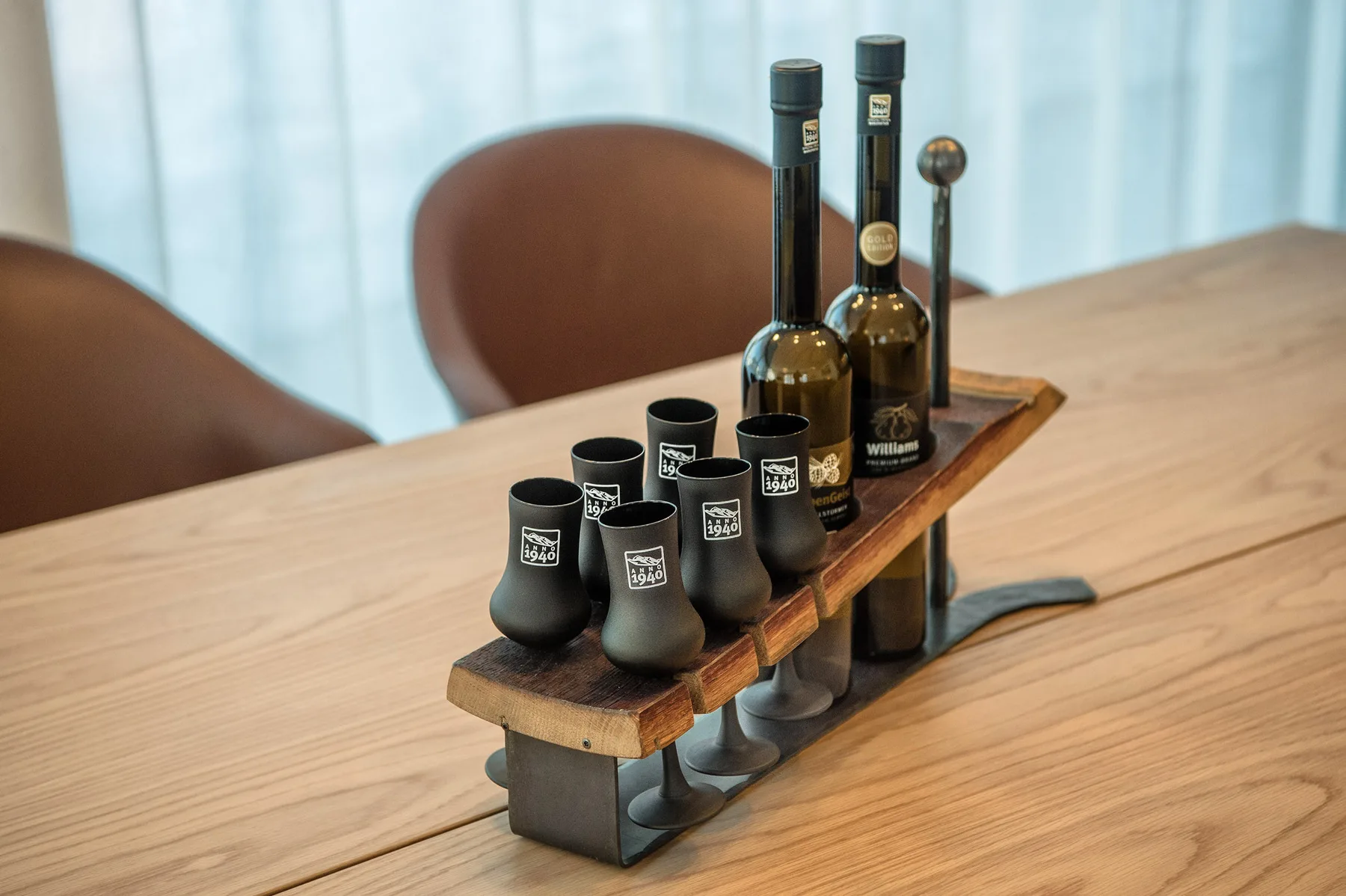 Una mesa de comedor de madera sostiene una bandeja con botellas y pequeños vasos de degustación.
