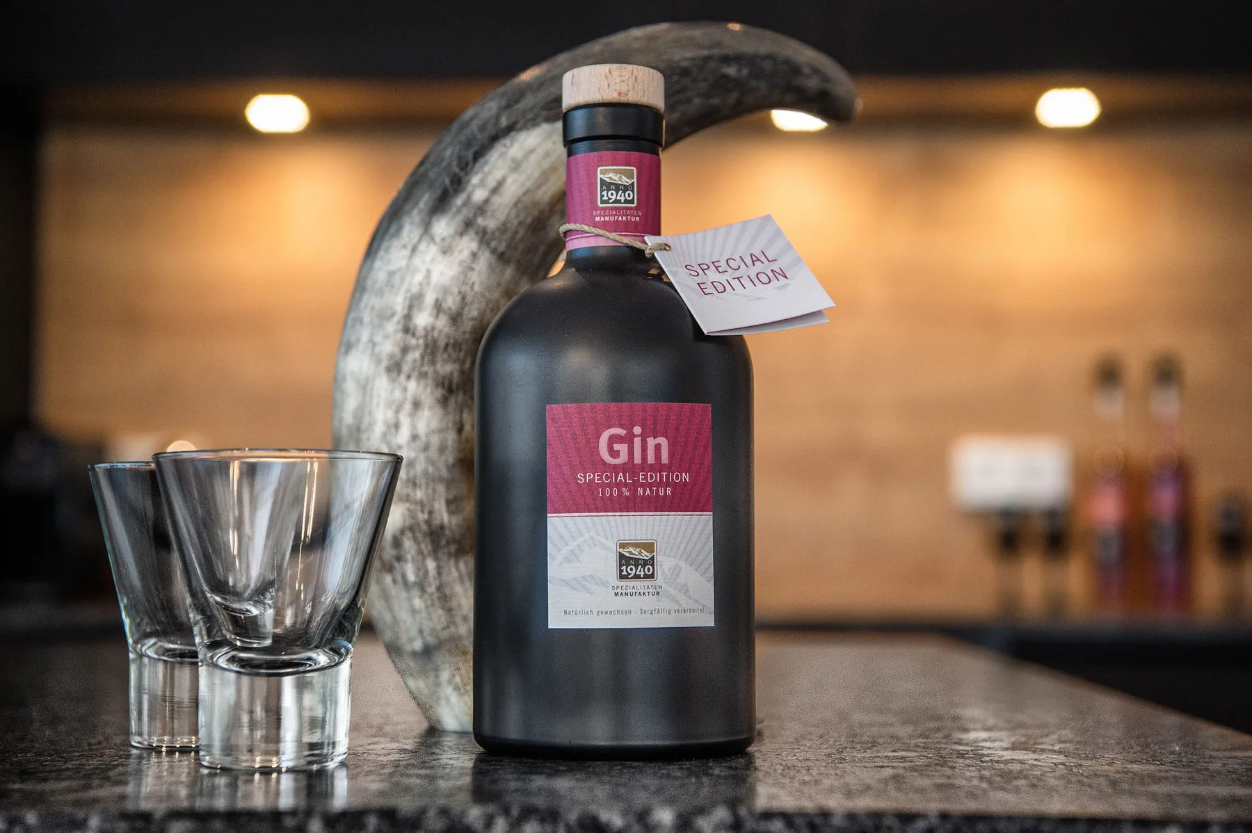 Una botella de ginebra y un vaso están sobre una encimera en una habitación iluminada.