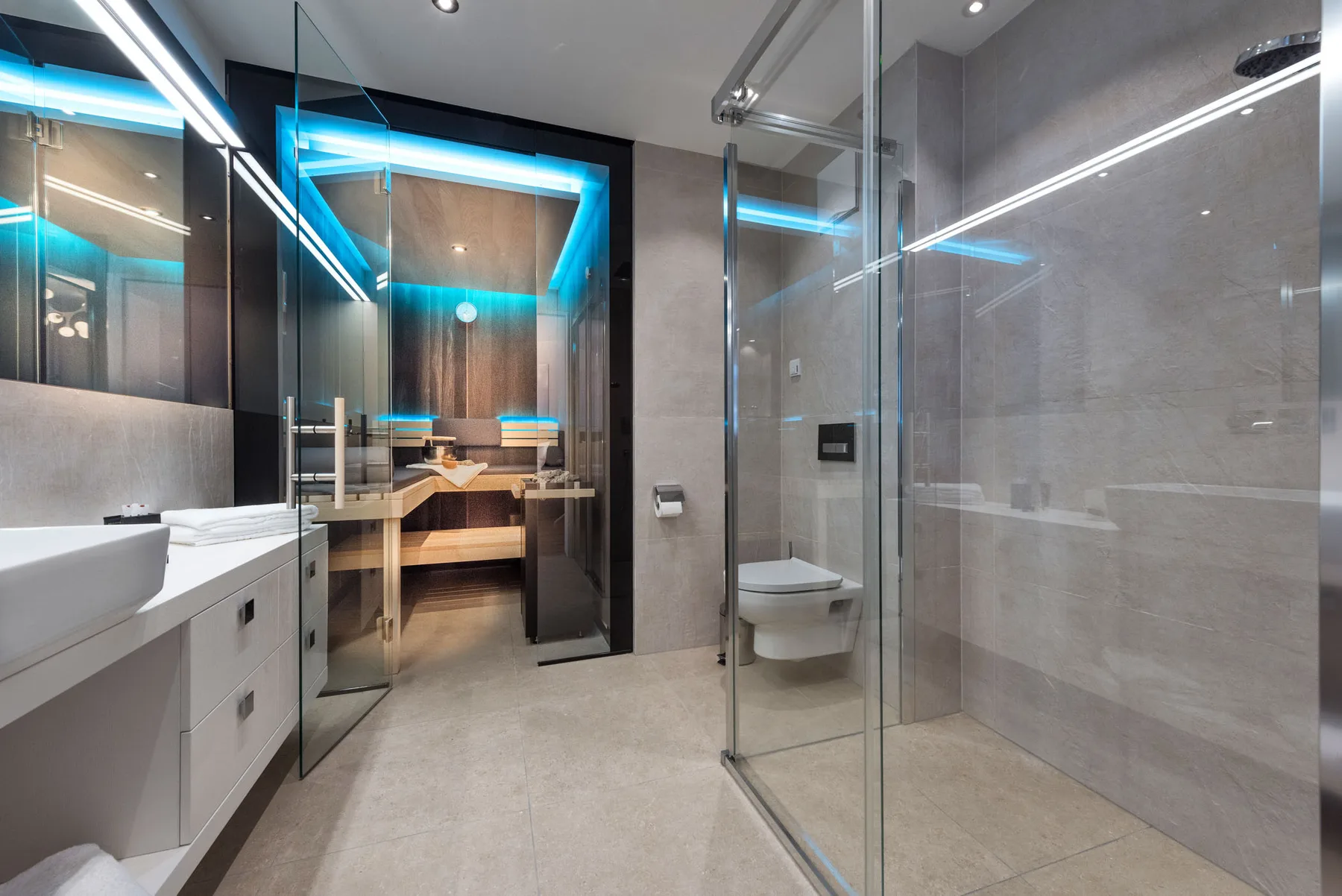 Un baño moderno con ducha de vidrio y un lavabo junto a una sauna de madera.