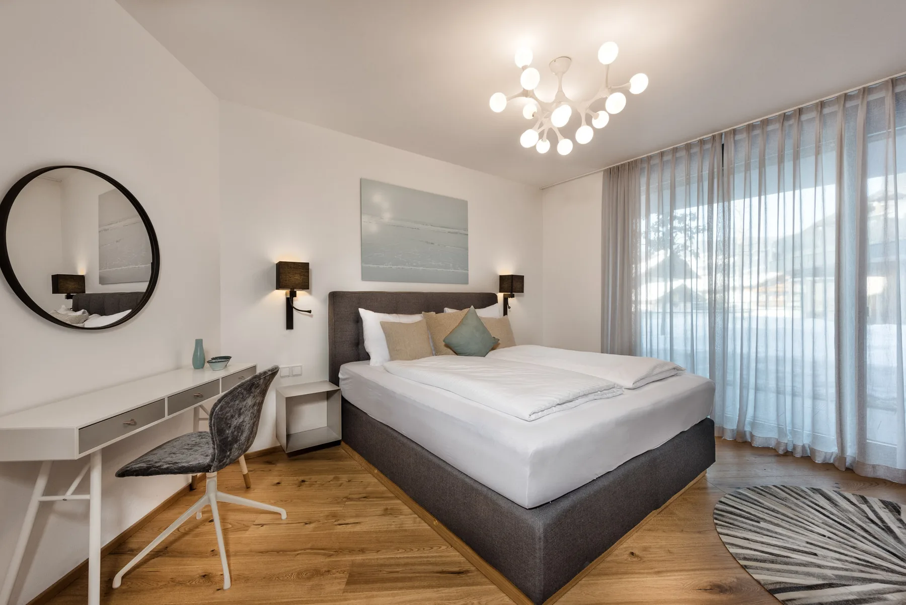 Un dormitorio con una cama grande, lámparas de mesilla y cortinas sobre una ventana.