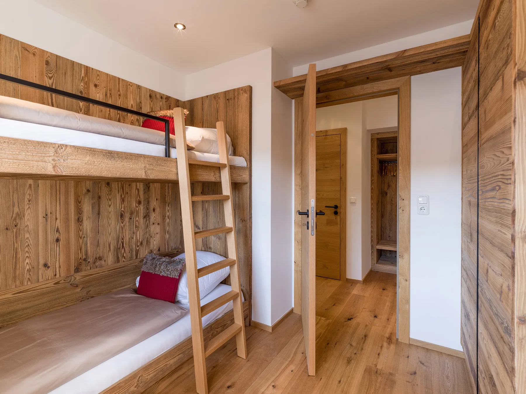 Un dormitorio revestido de madera con literas y una puerta abierta.