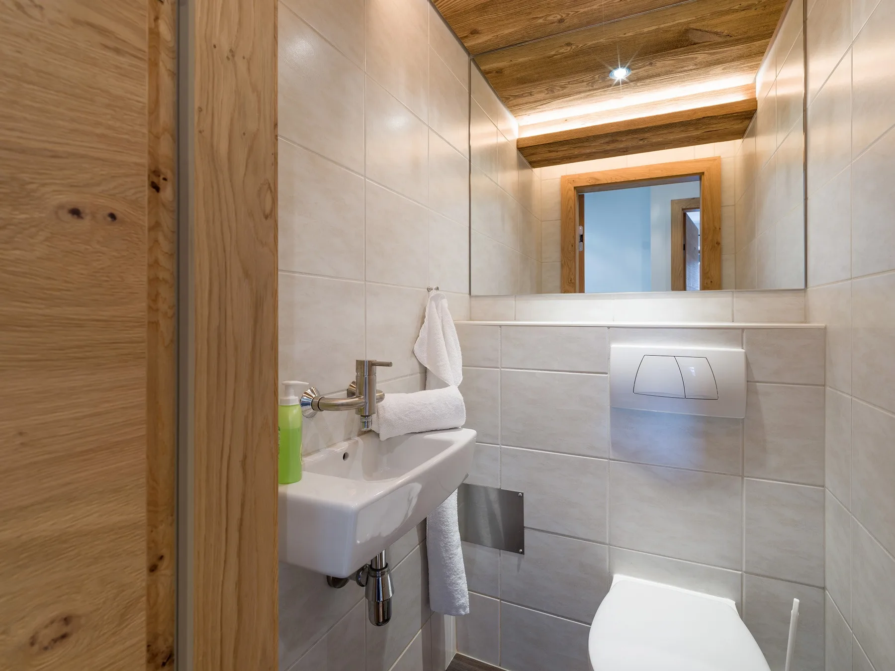 Un baño con azulejos, un lavabo suspendido y un inodoro.