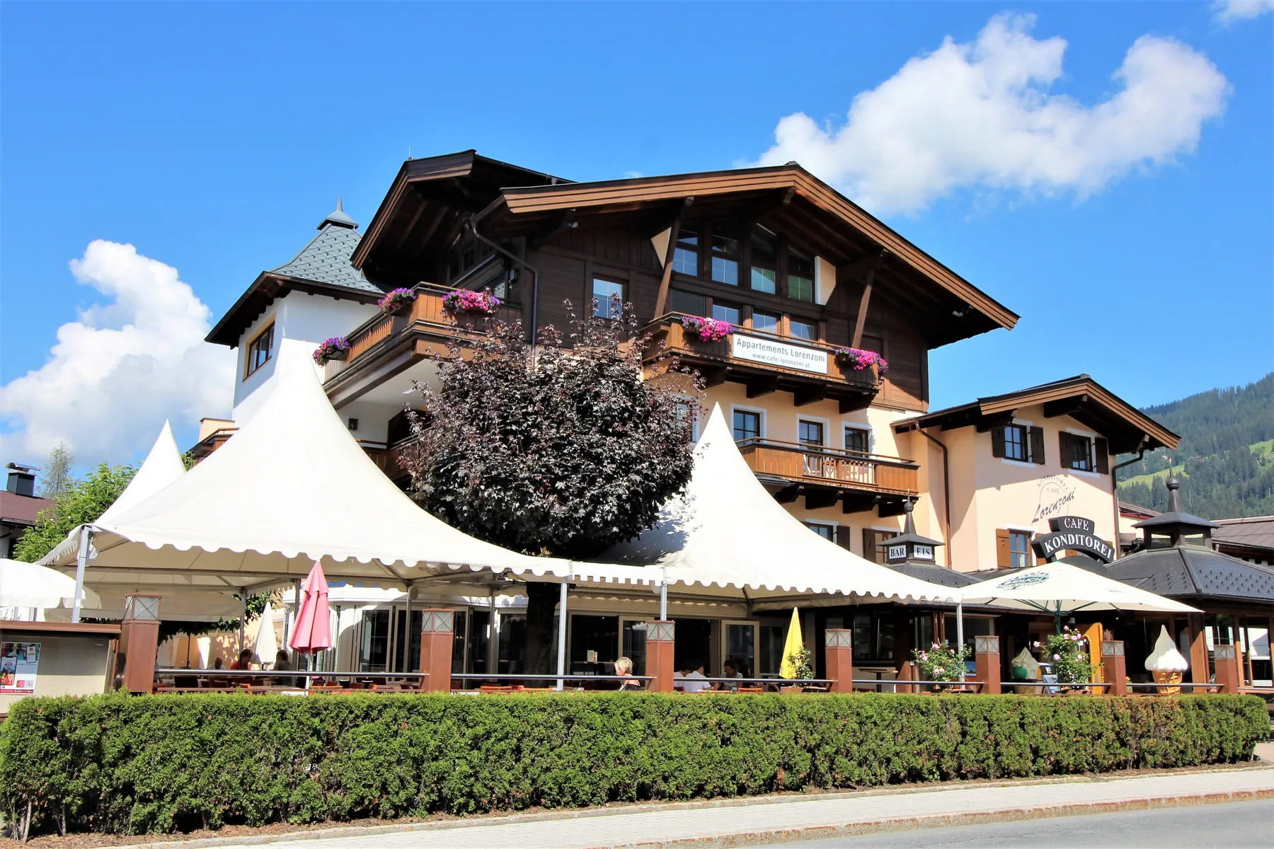Zona común: Un edificio de hotel con mesas al aire libre bajo toldos blancos.