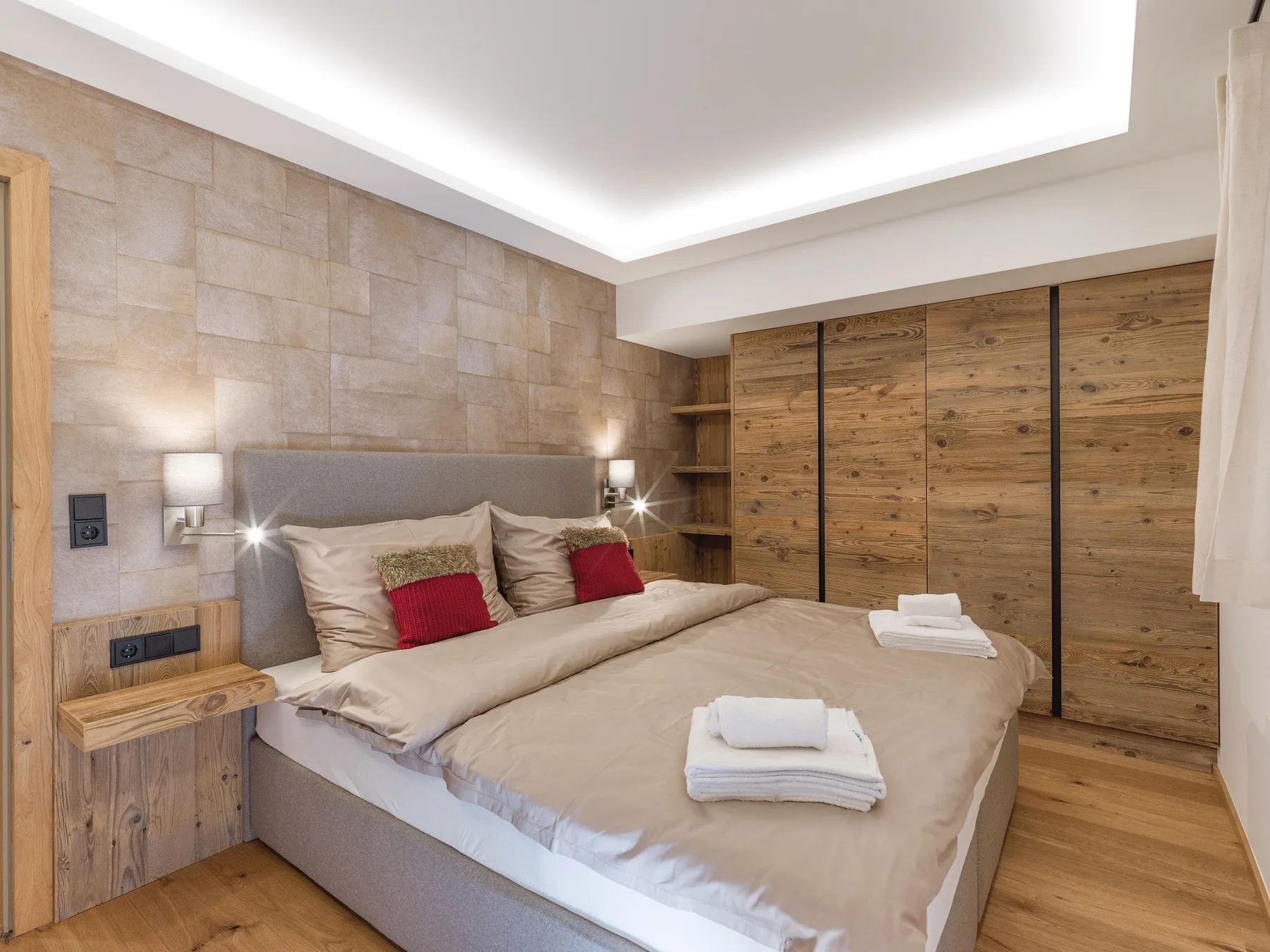 Un dormitorio con una cama grande, almacenamiento de madera y paredes con diseño de piedra.