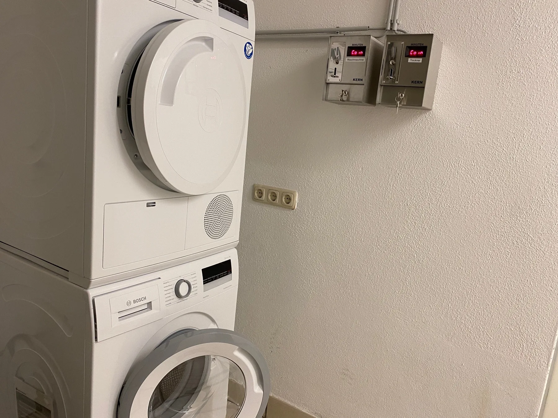 Zona común: Zona de lavandería con lavadoras apiladas y controles en la pared.