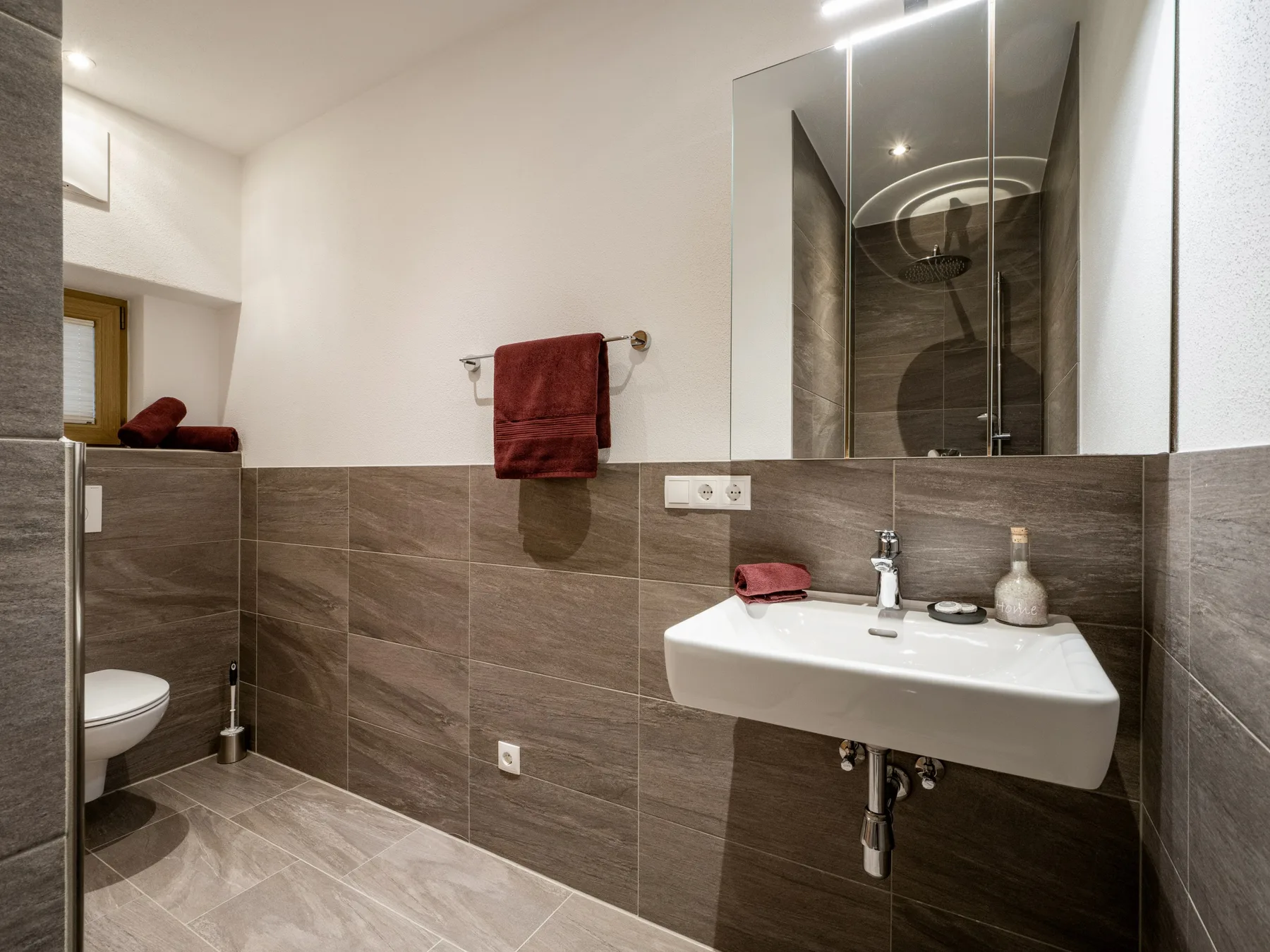 Un baño moderno con un lavabo suspendido y una ducha detrás de una mampara de vidrio.
