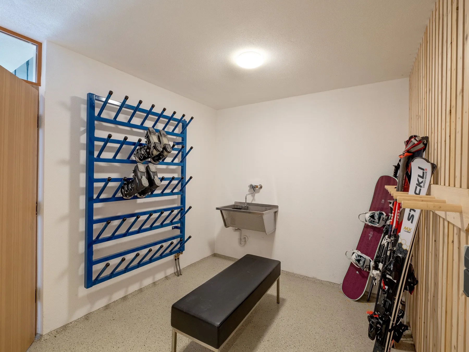 Zona común: Un cuarto para guardar esquís, con un estante azul y un banco.