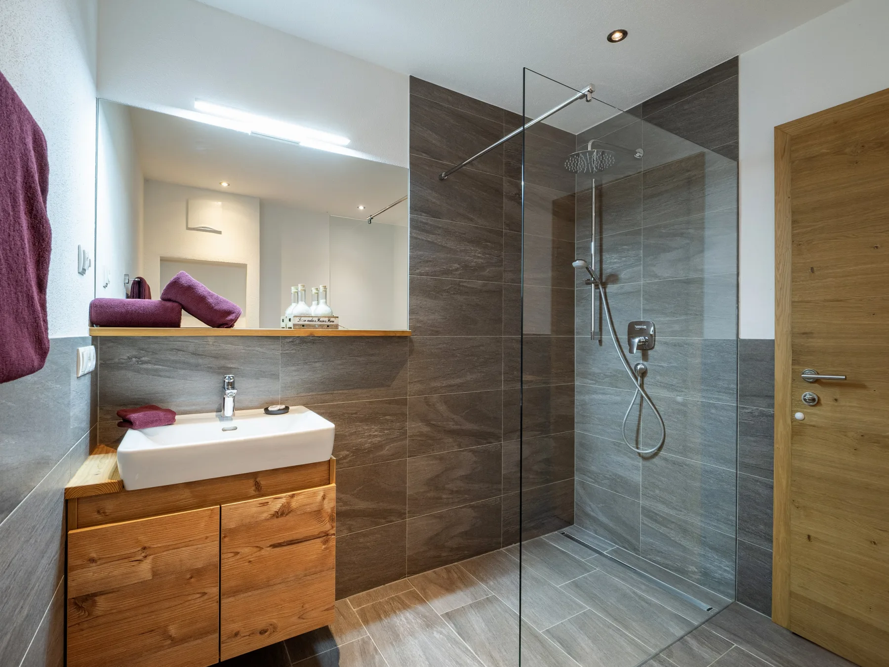Un baño moderno con un mueble de madera y una ducha de vidrio.