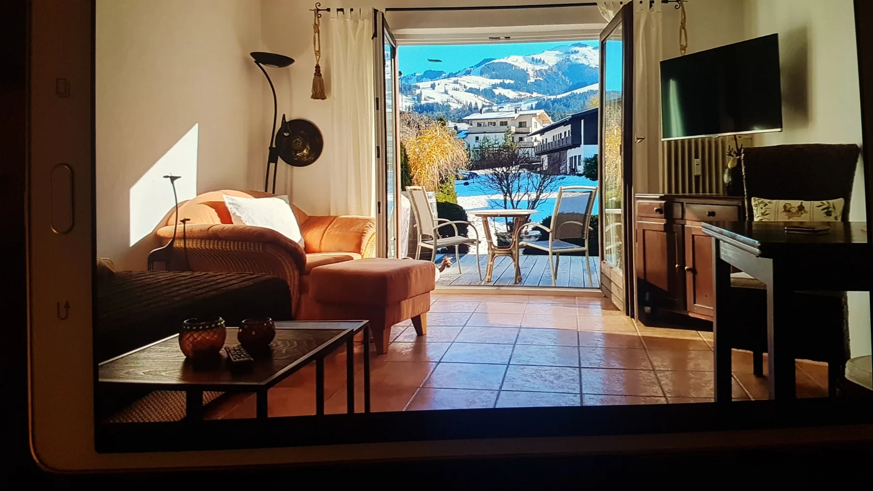 Una sala de estar se abre a un balcón con asientos al aire libre y vistas a las montañas.