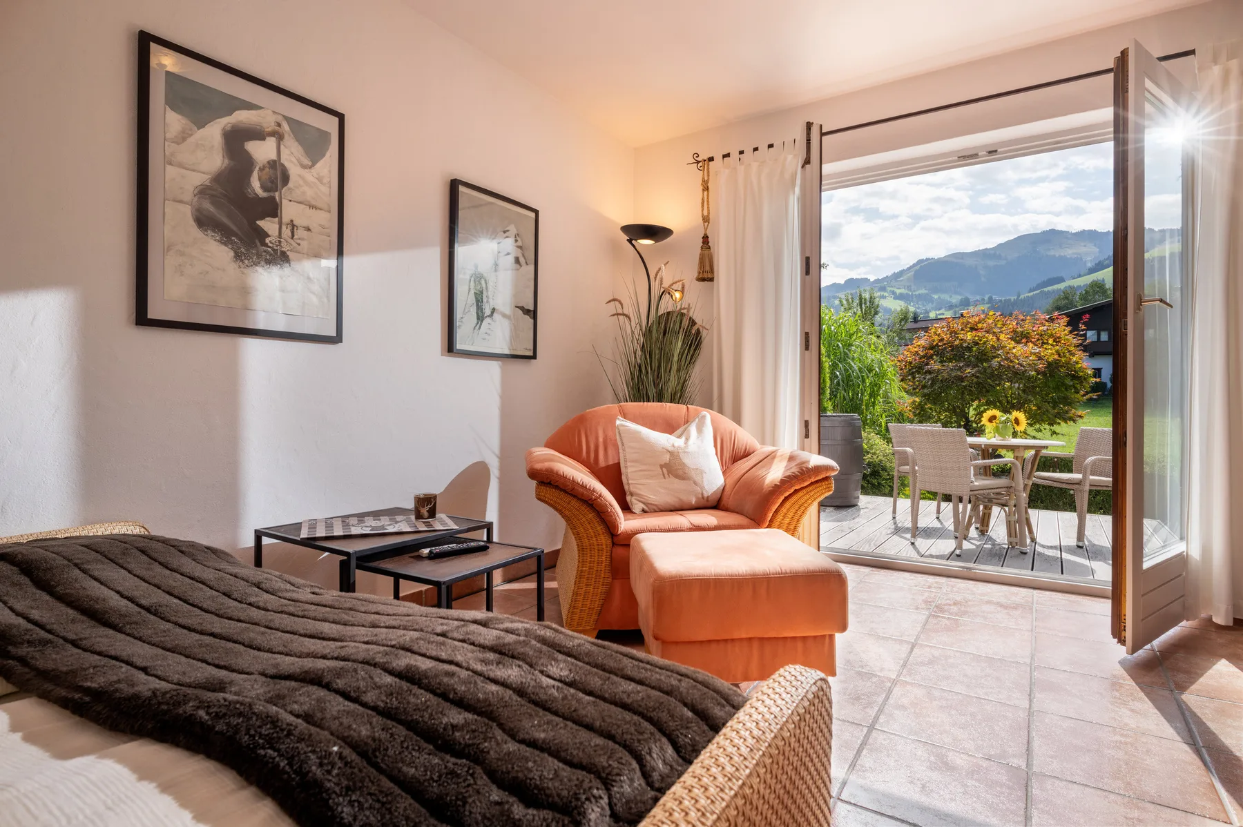 A bedroom seating area opens onto a patio and garden with mountain views.