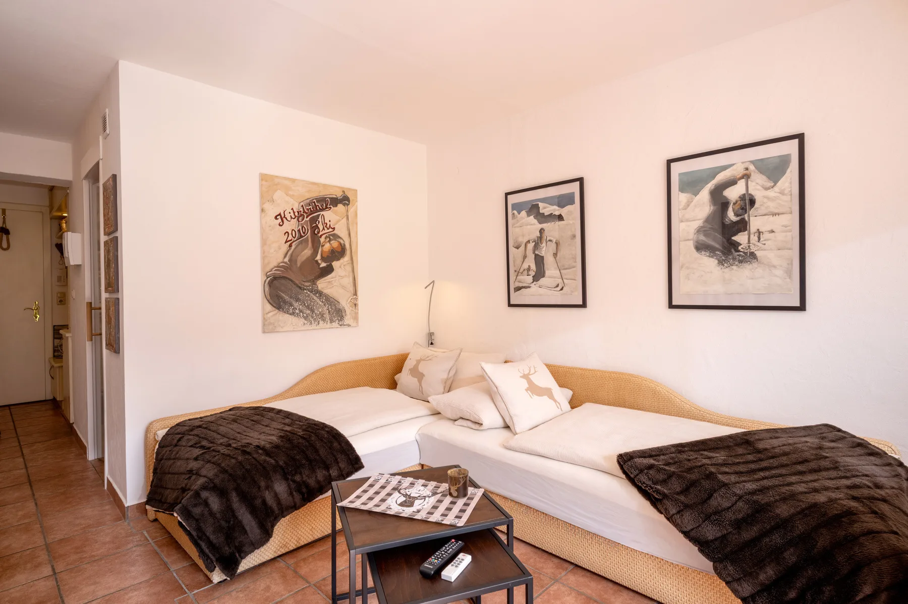 Un dormitorio luminoso con dos camas, cuadros enmarcados y una mesa pequeña.