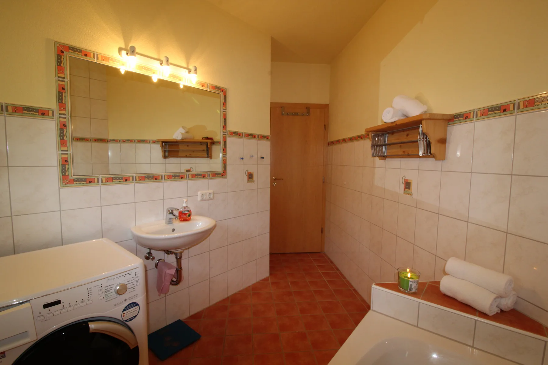 A tiled bathroom with a sink, washing machine, and bathtub.