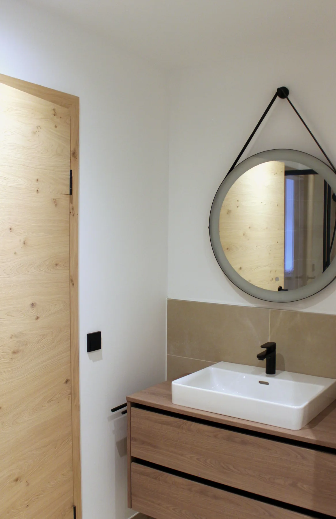 A bathroom vanity with a round mirror above a white sink.