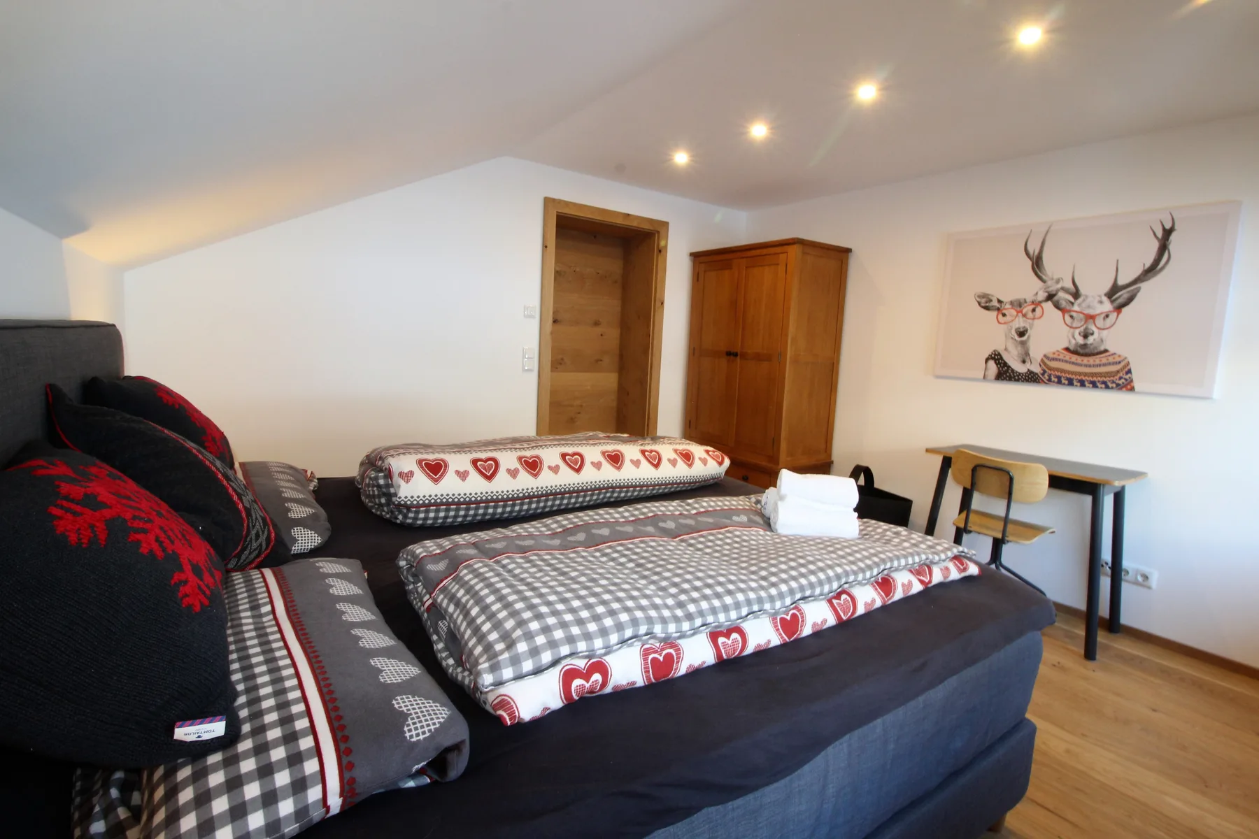 A bedroom with patterned bedding and a wooden wardrobe.