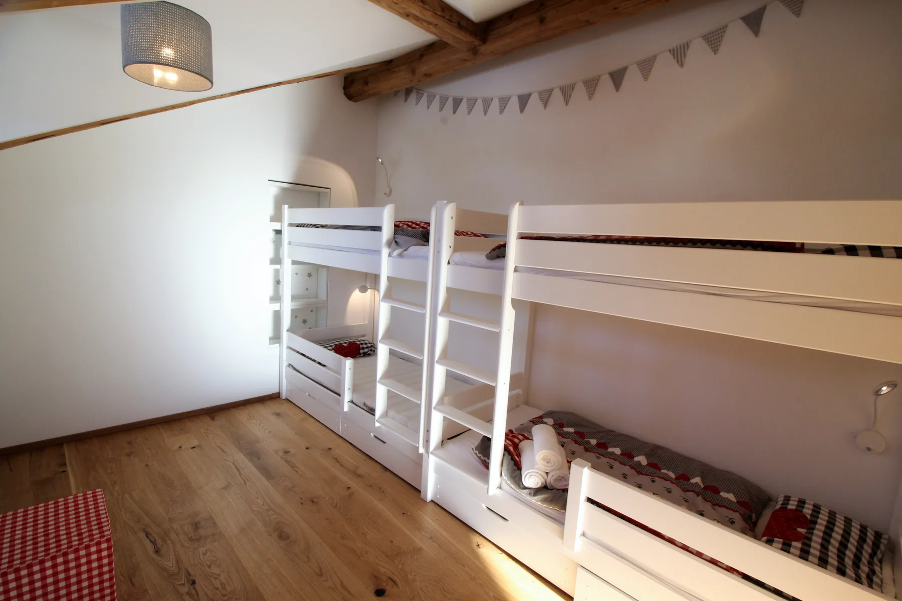 A bedroom with white bunk beds and a wooden floor.